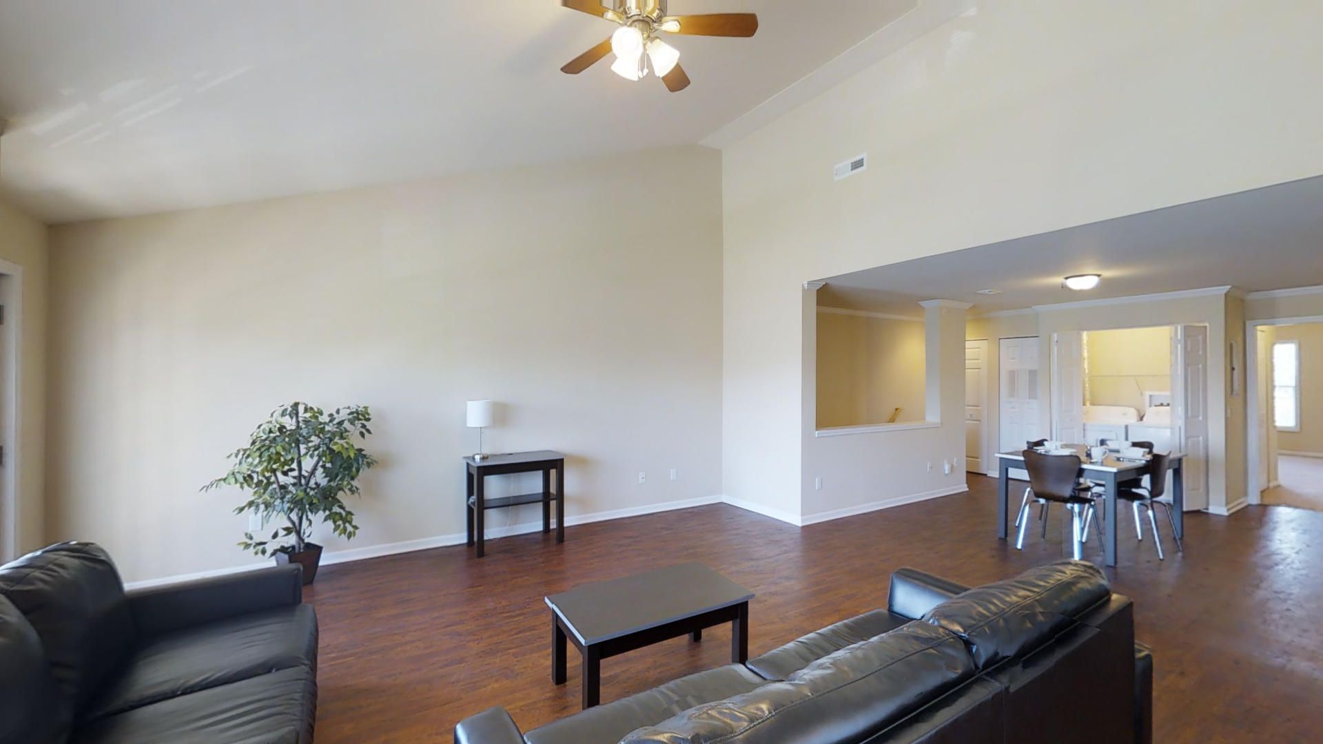 A living room with a couch , coffee table , and ceiling fan.