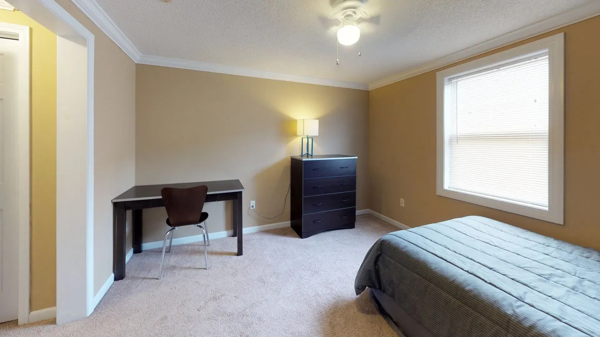 A bedroom with a bed a desk and a window