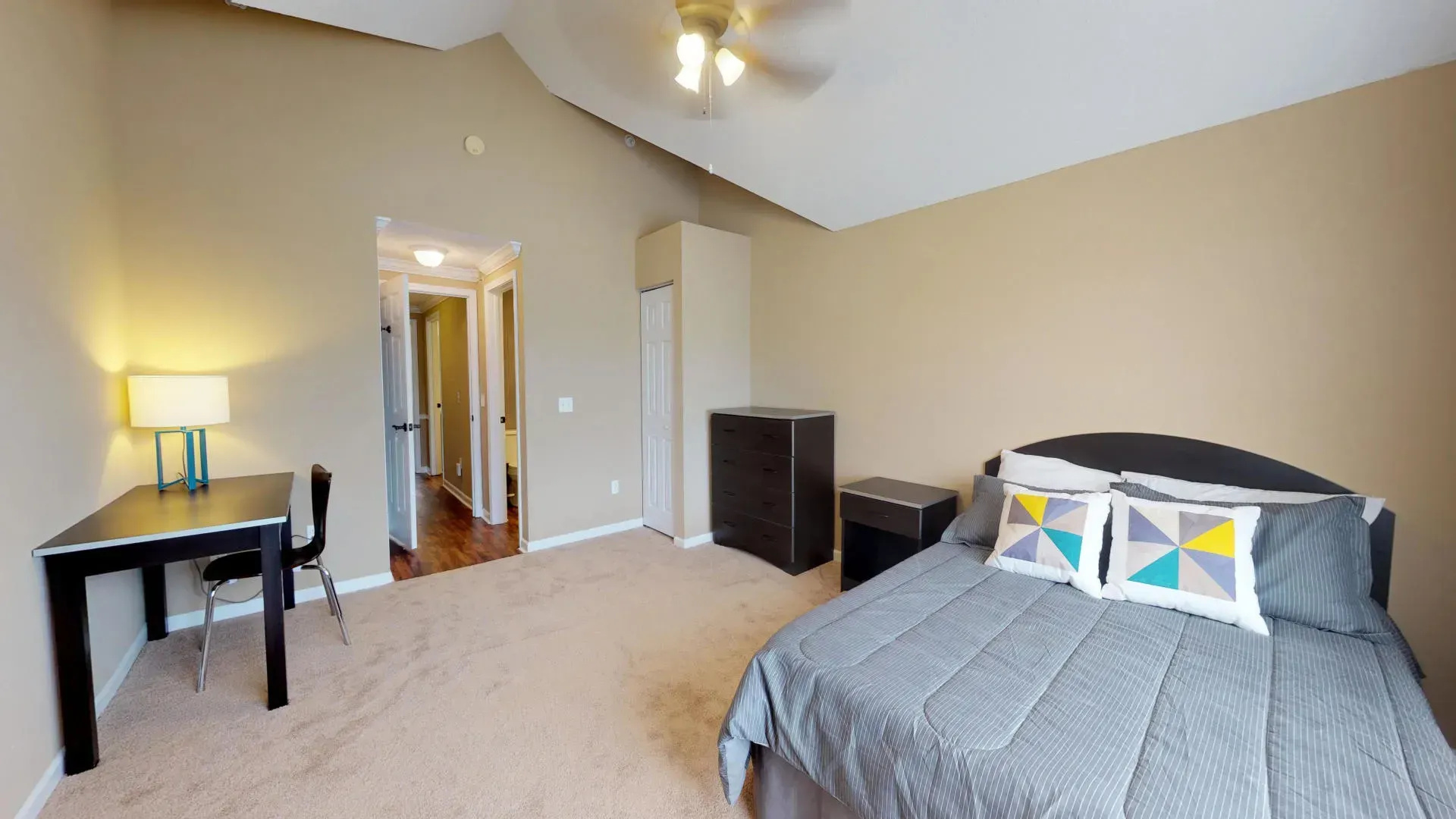 A bedroom with a large bed and a desk
