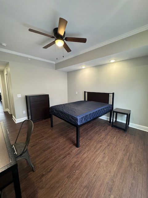 Spacious bedroom with ceiling fan and wood-style flooring