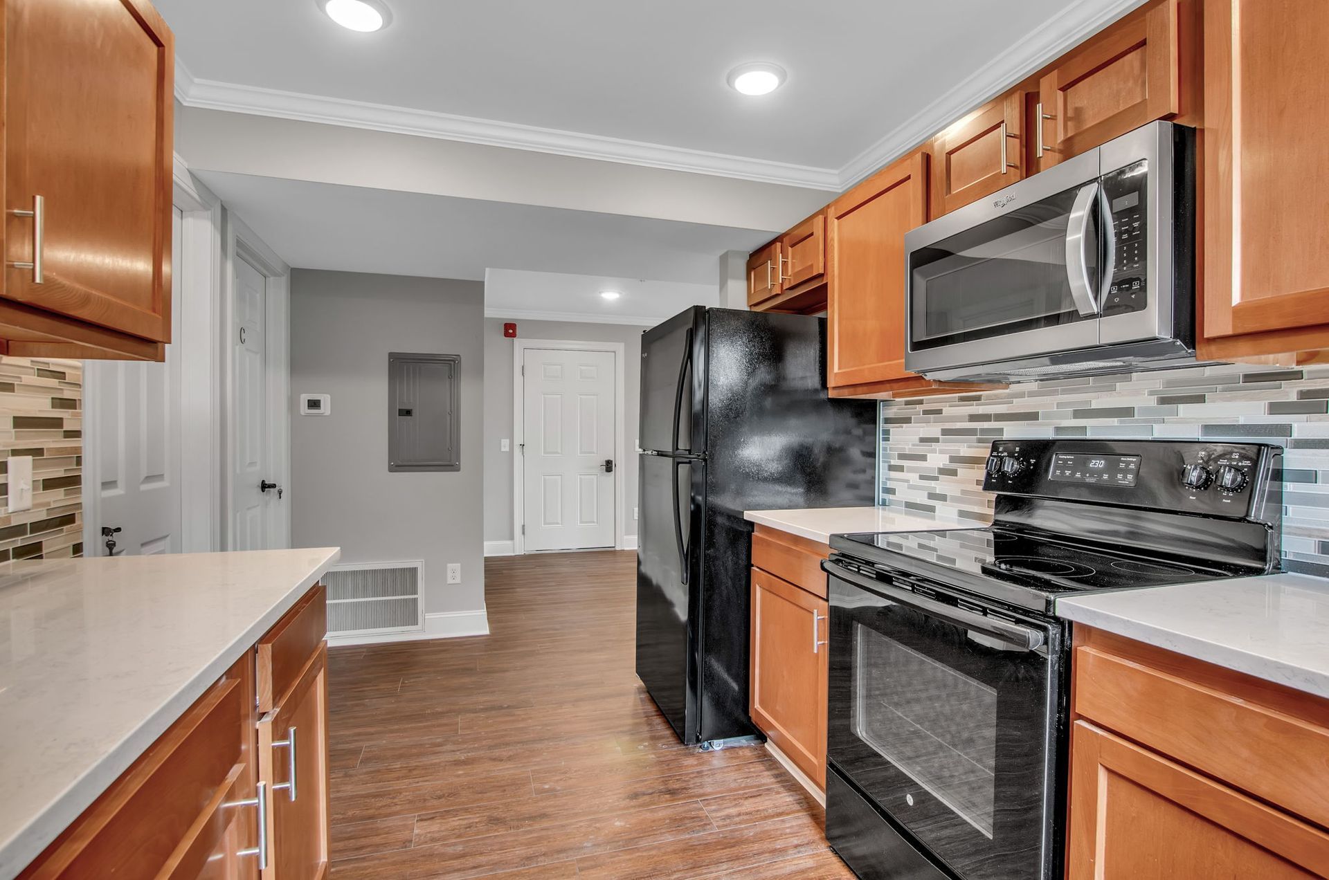 A kitchen with wooden cabinets , stainless steel appliances , and a refrigerator.