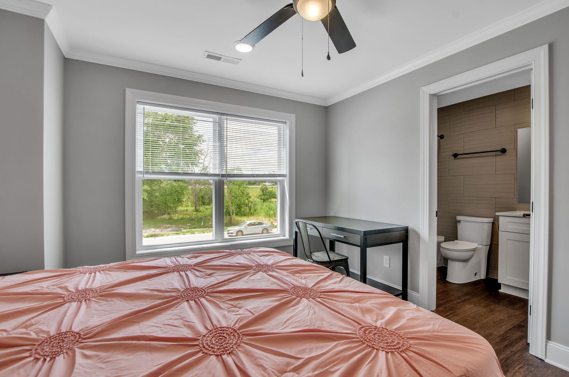 A bedroom with a bed , desk , toilet and window.