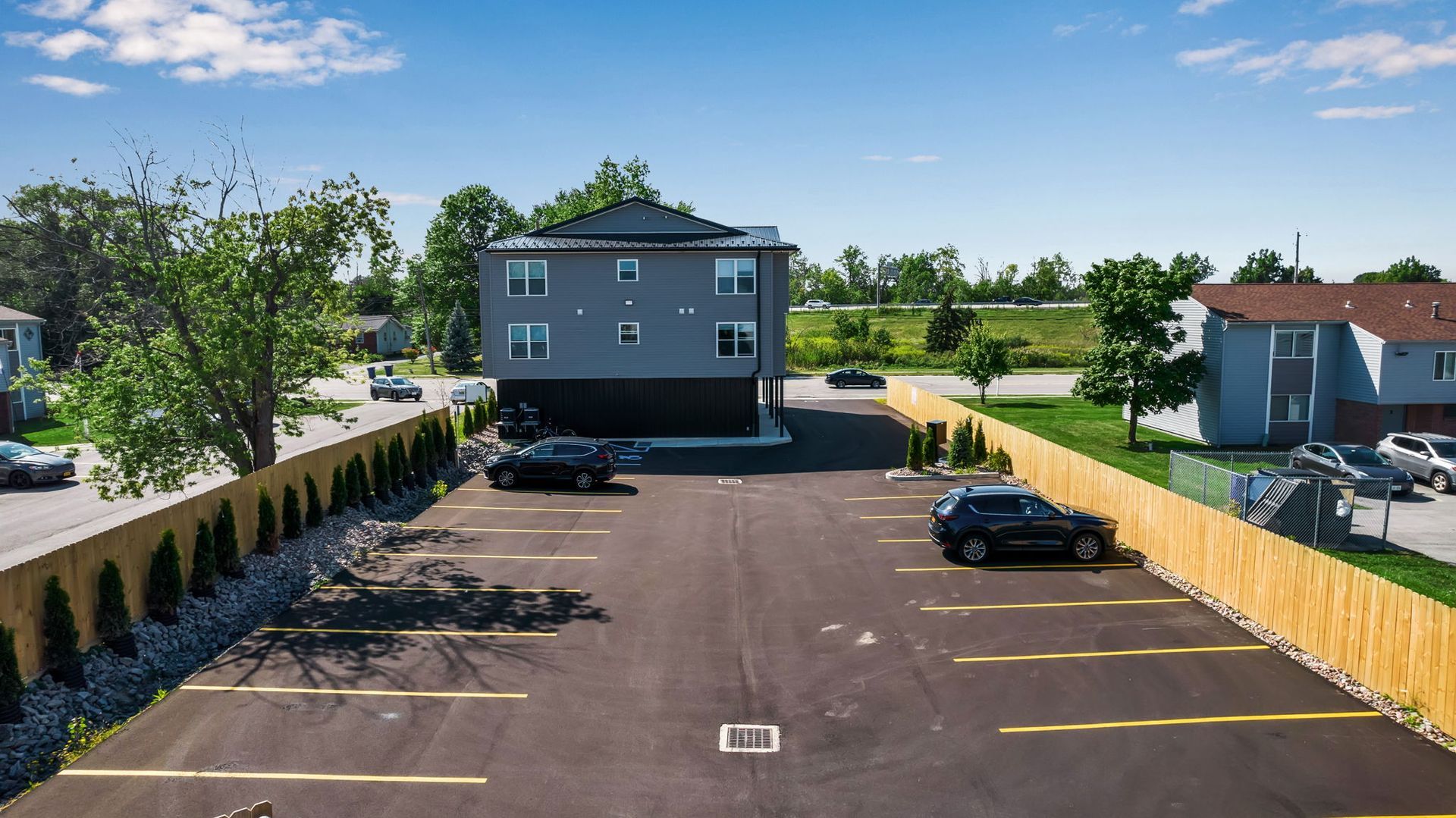 An aerial view of a parking lot with cars parked in front of a building.