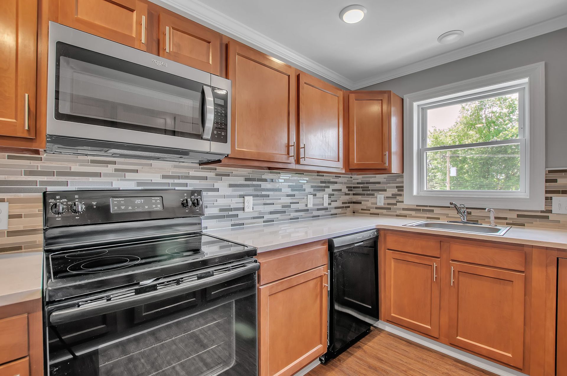 A kitchen with wooden cabinets , stainless steel appliances , and a window.
