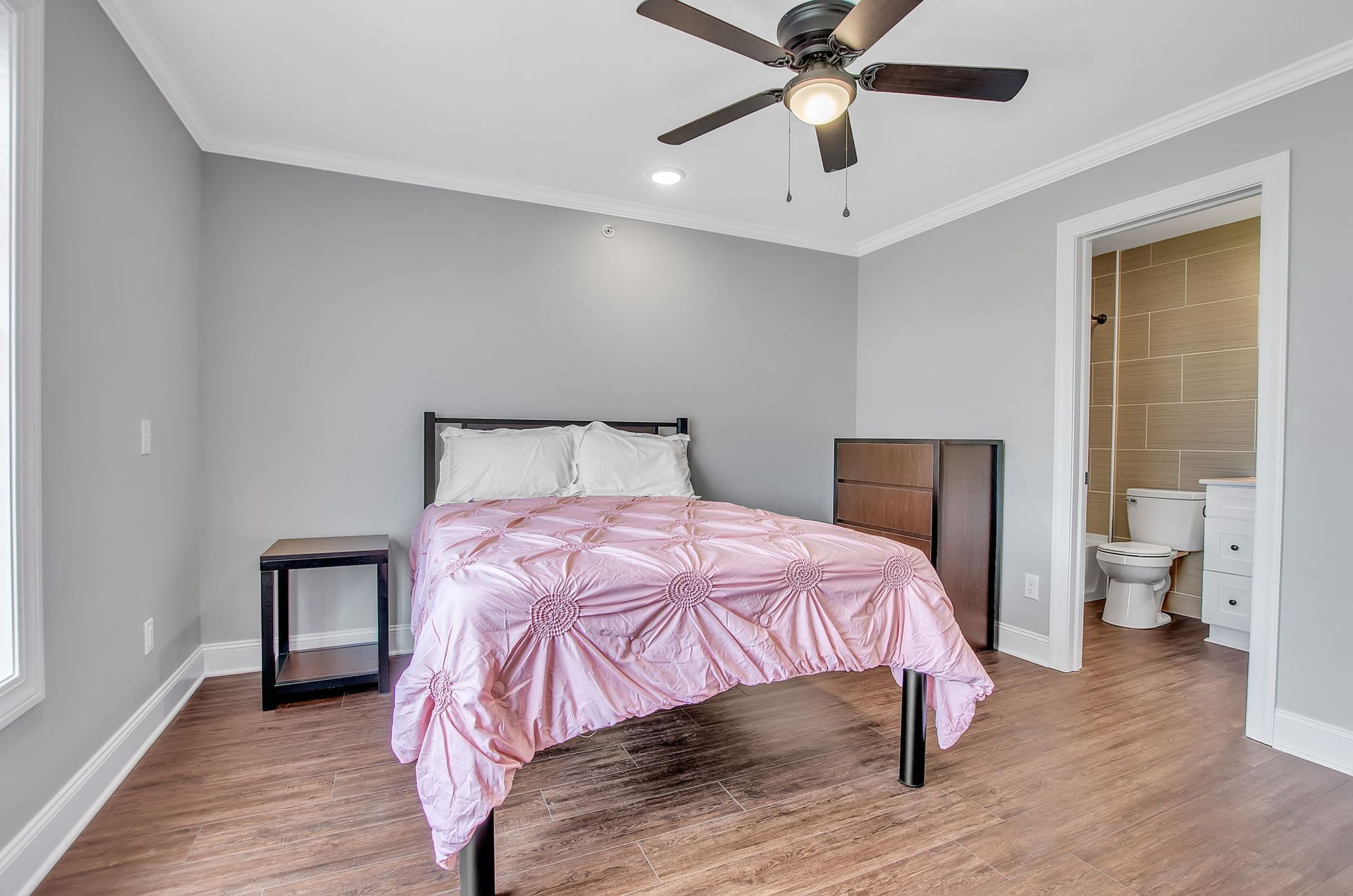 A bedroom with a bed , nightstand , and ceiling fan.