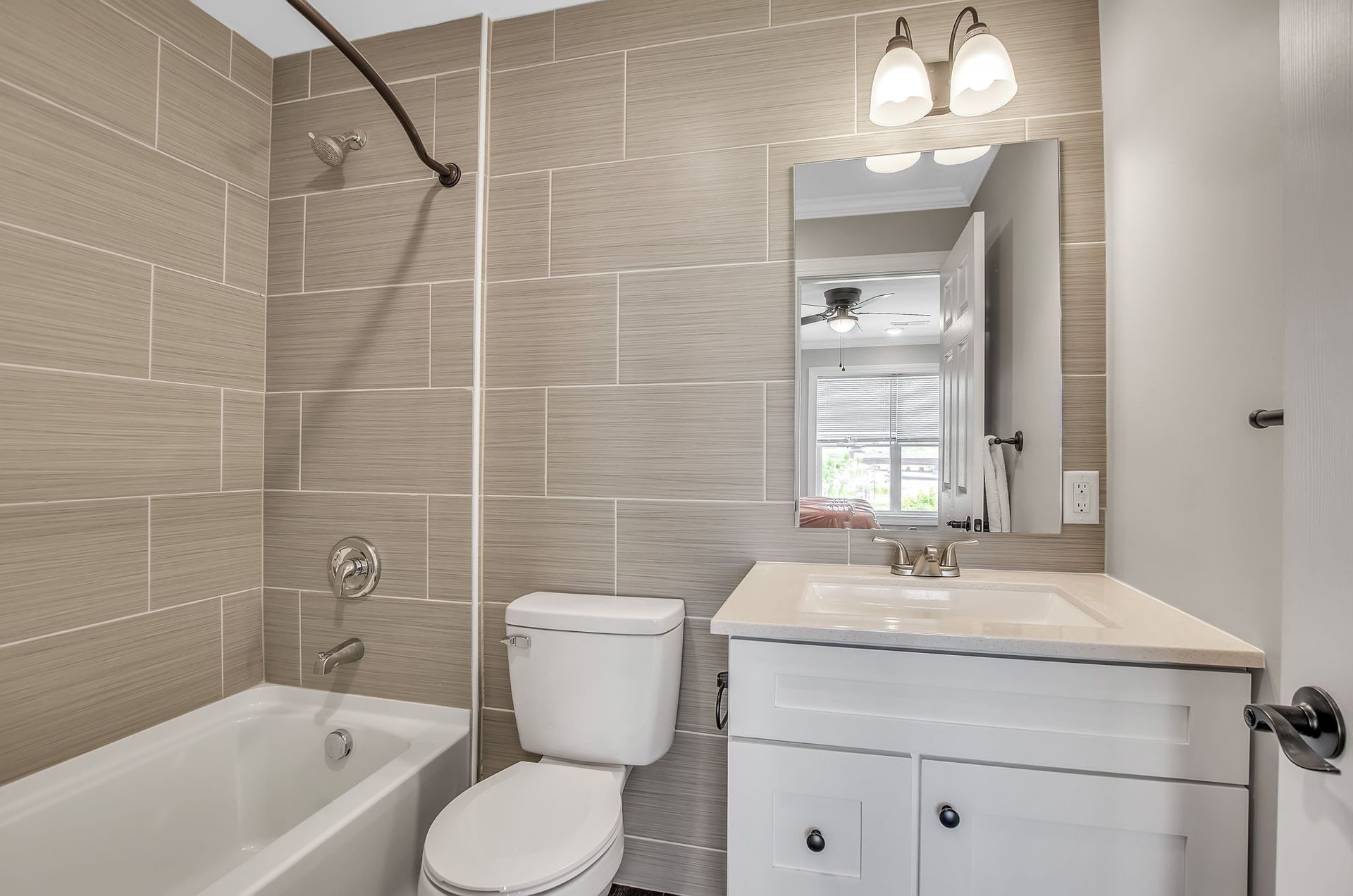 A bathroom with a toilet , sink , bathtub and mirror.