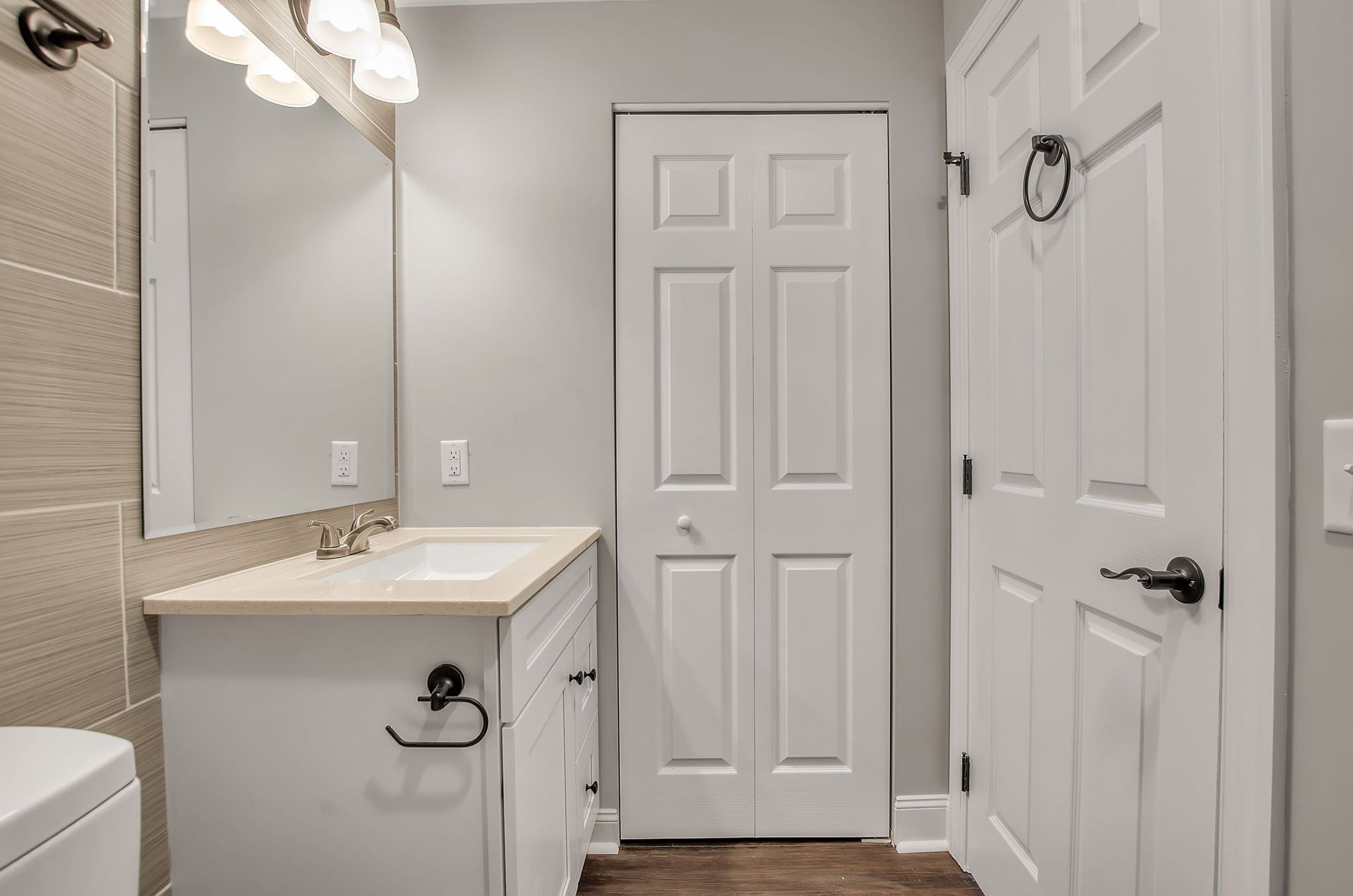 A bathroom with a sink , toilet , mirror and closet.