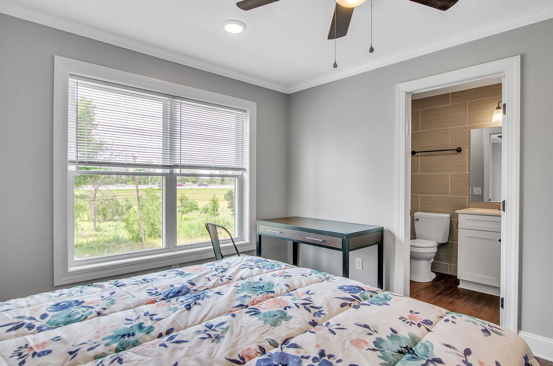 A bedroom with a ceiling fan , a bed , a window and a bathroom.