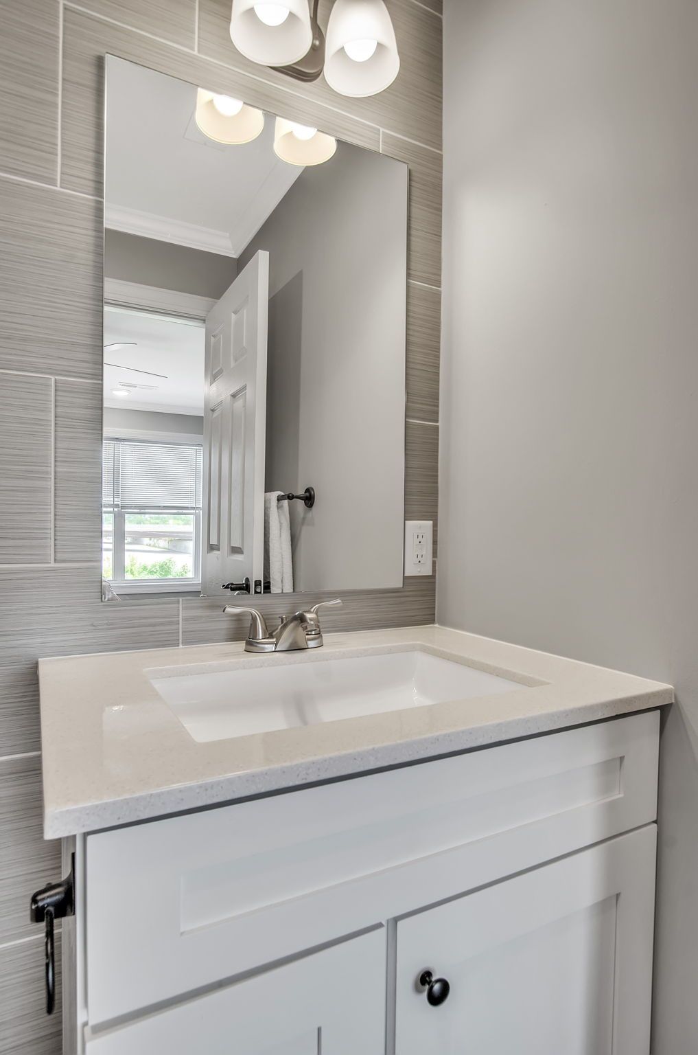 A bathroom with a sink , mirror and light fixtures.