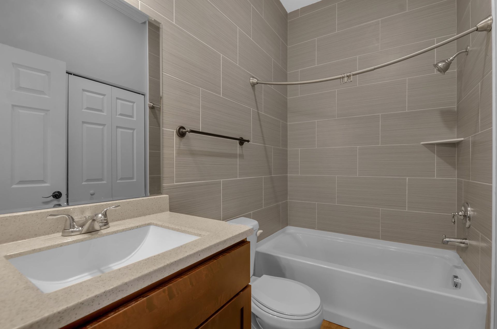 A bathroom with a sink , toilet , tub and mirror.