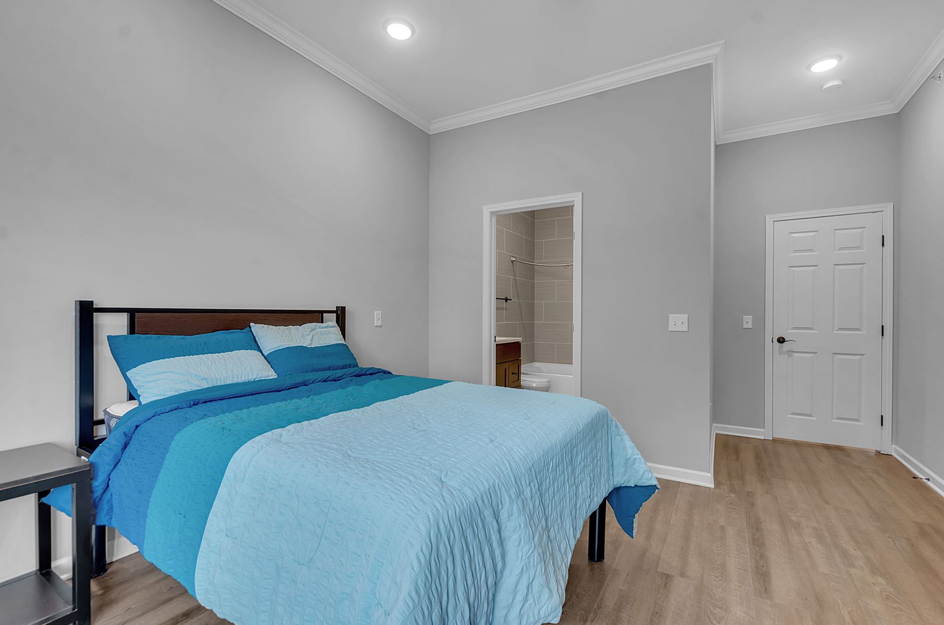 A bedroom with a bed and a bathroom in the background.
