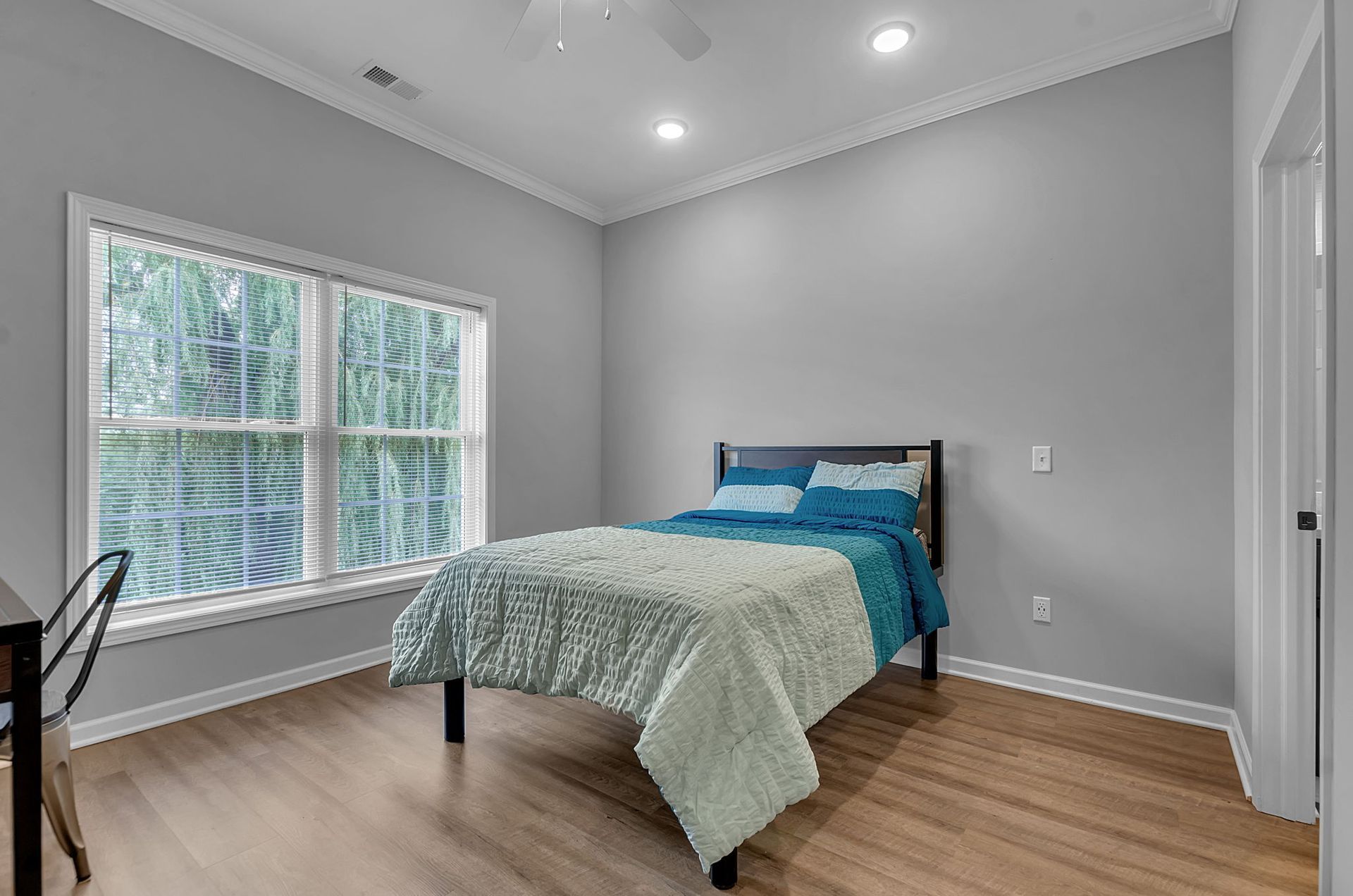 A bedroom with a bed , desk , and two windows.
