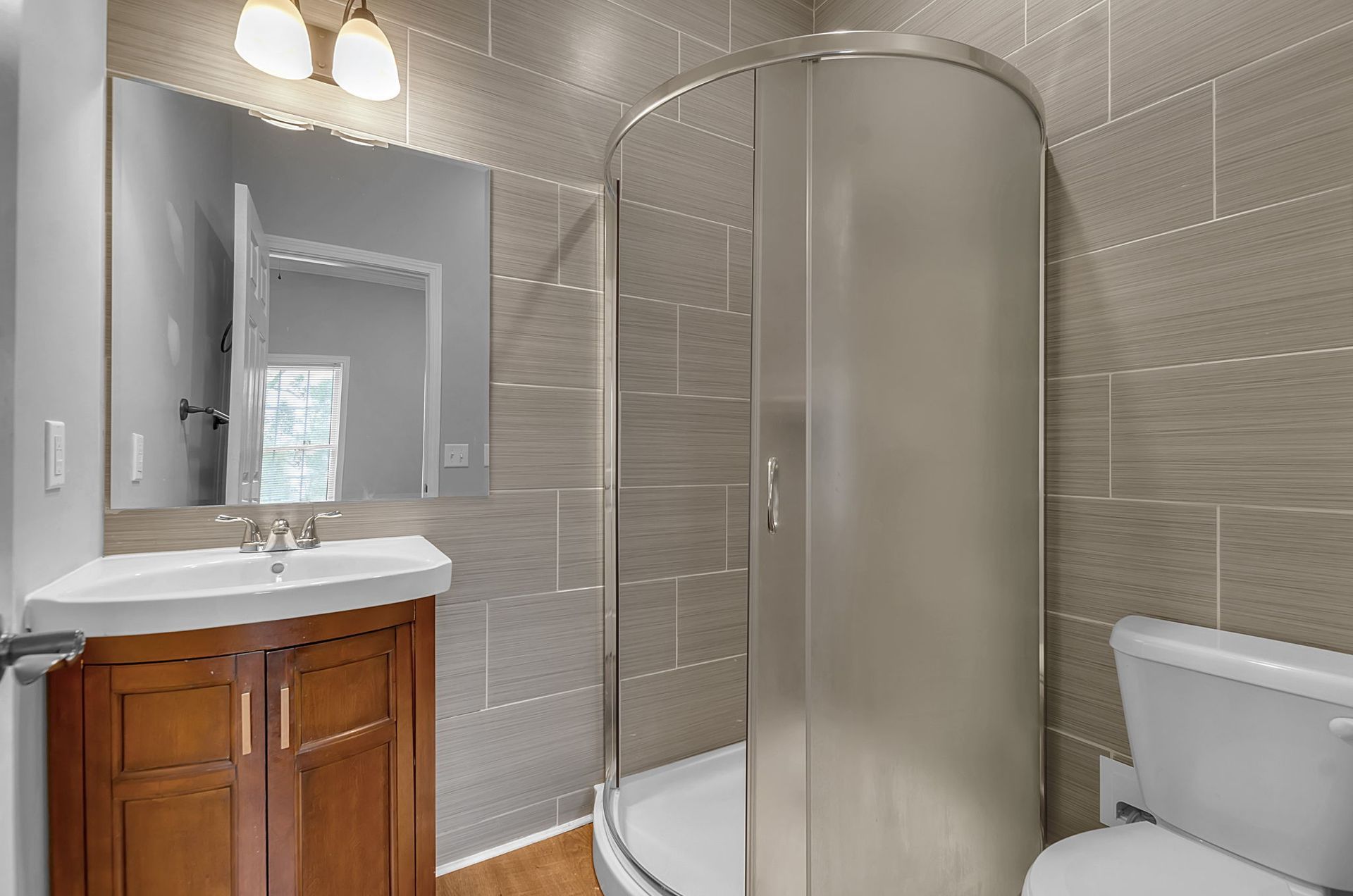 A bathroom with a sink , toilet , shower and mirror.