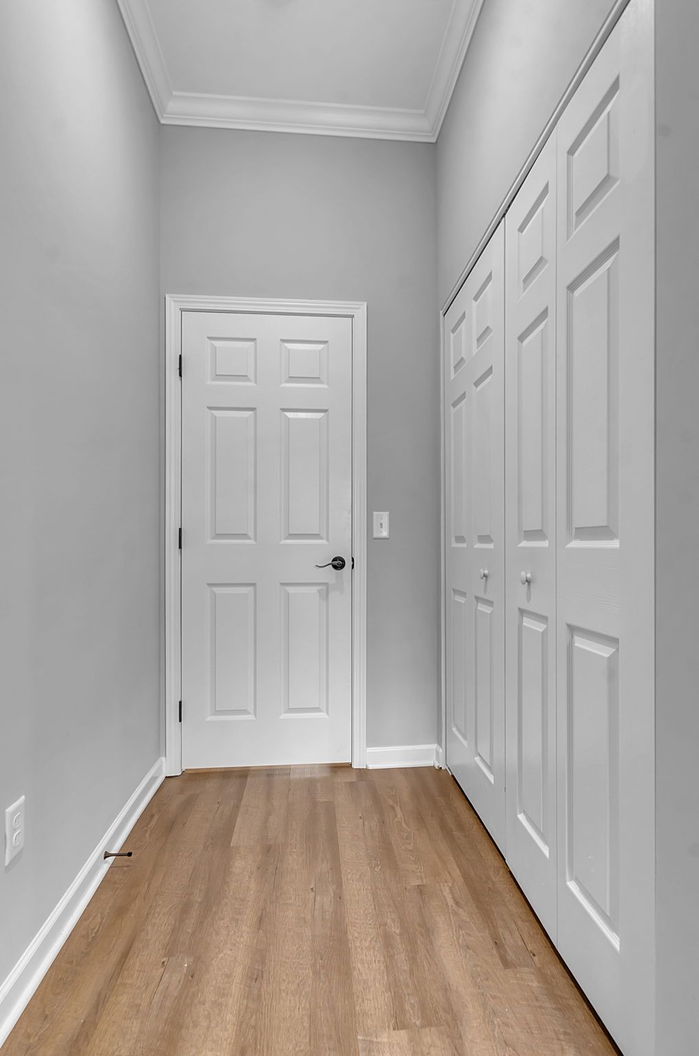 A hallway with hardwood floors and white doors in a house.