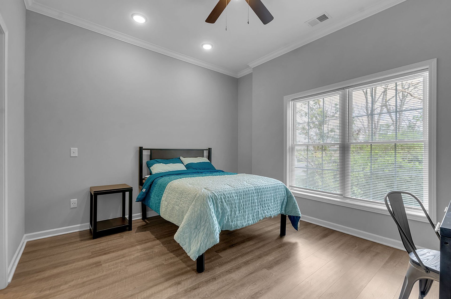 A bedroom with a bed , window , nightstand and ceiling fan.