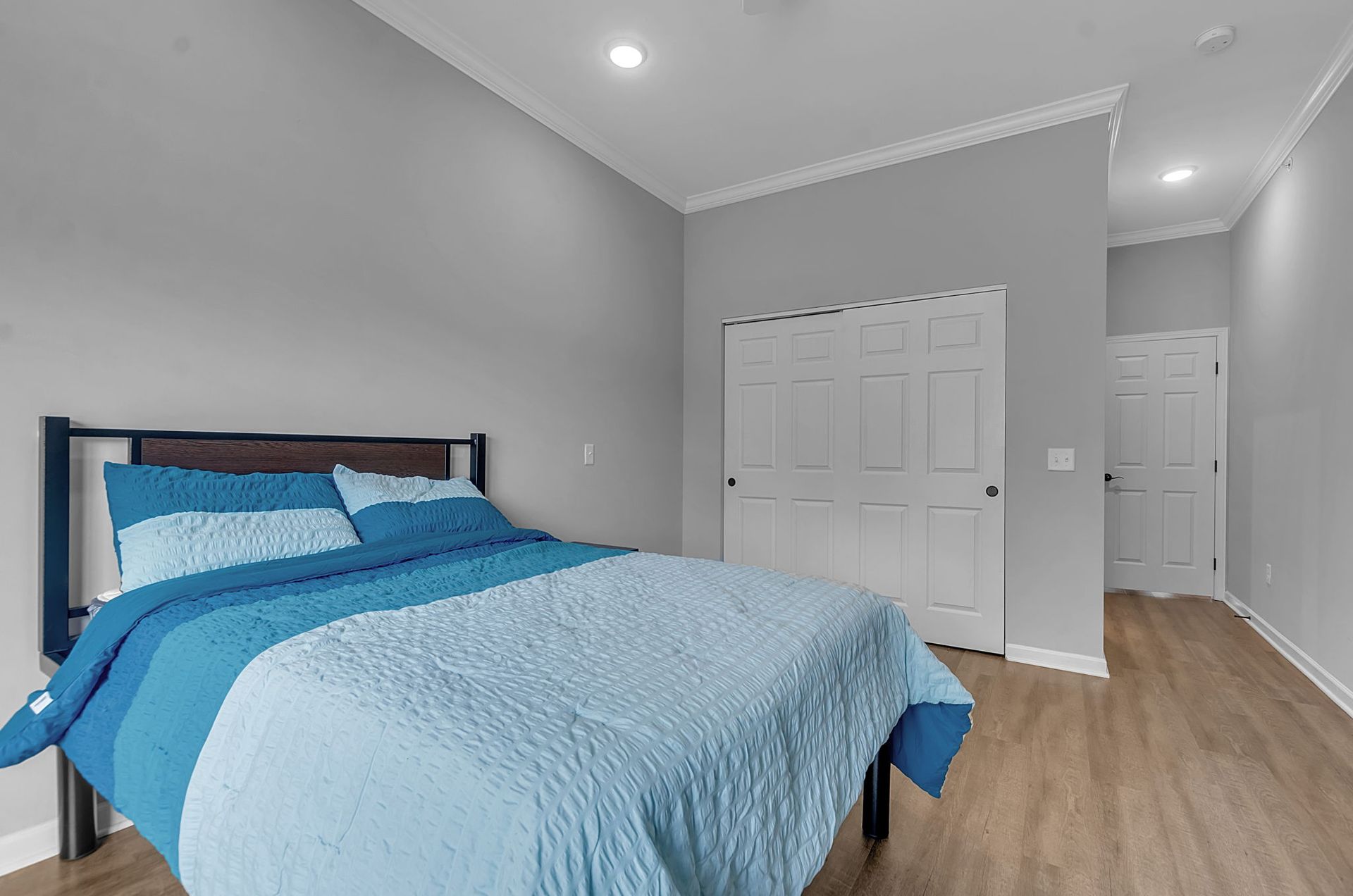 A bedroom with a bed , closet , and wooden floor.