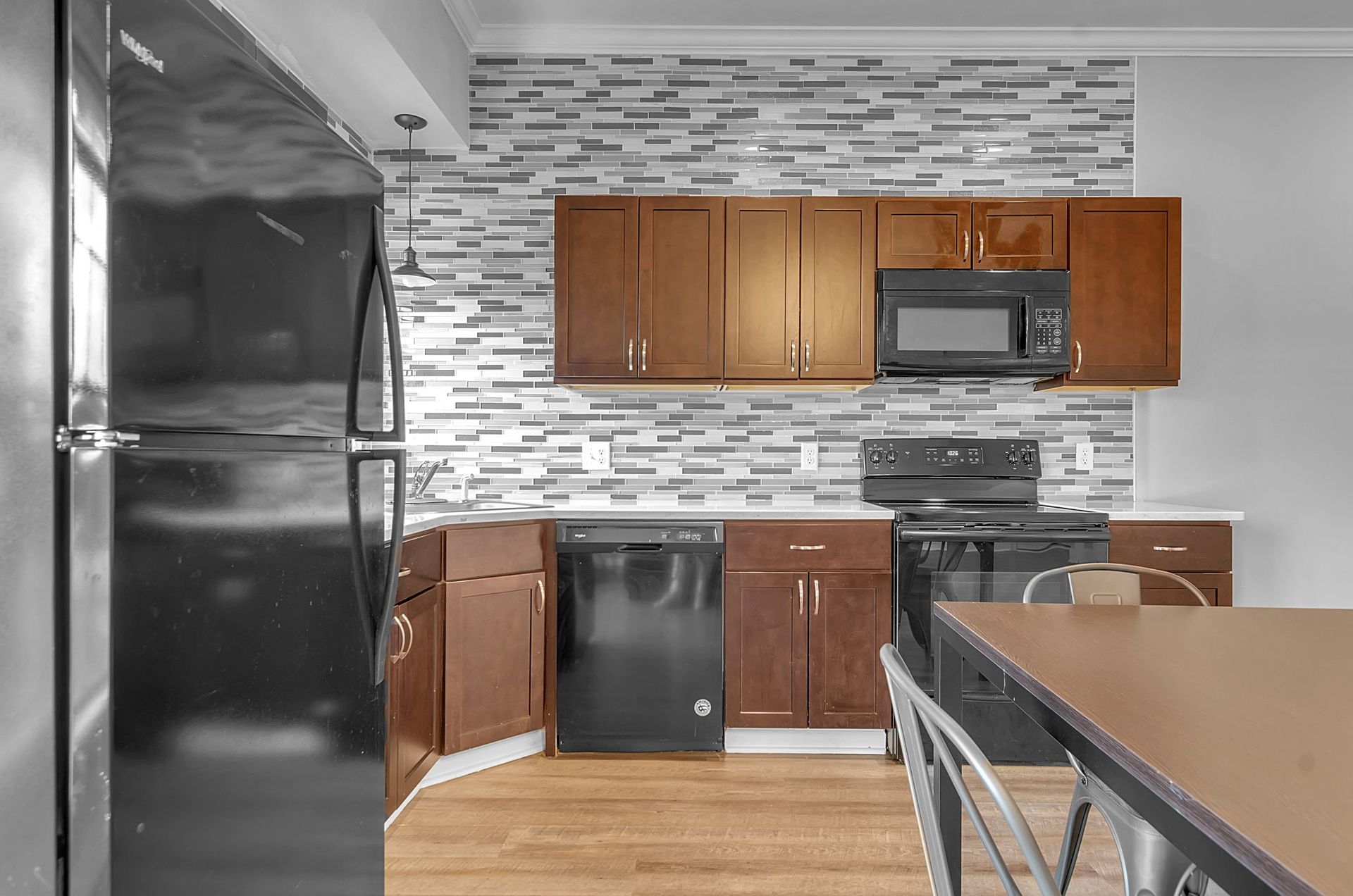 A kitchen with stainless steel appliances , wooden cabinets , a table and chairs.