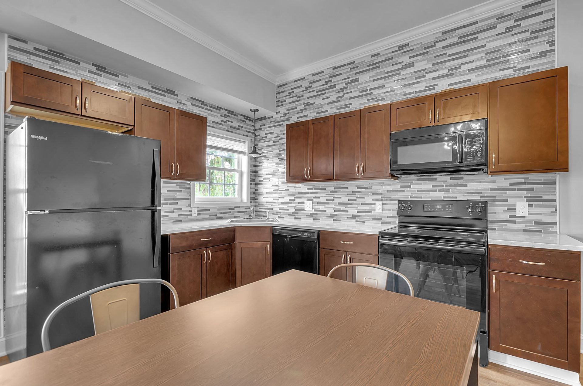 A kitchen with a table , refrigerator , stove and microwave.