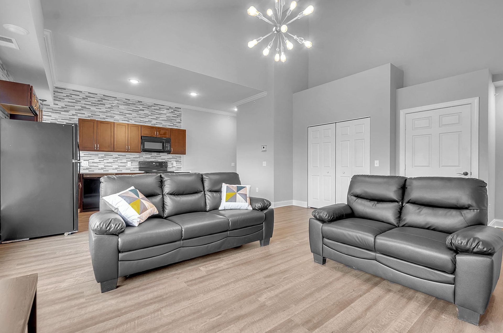 A living room with two couches and a kitchen in the background.