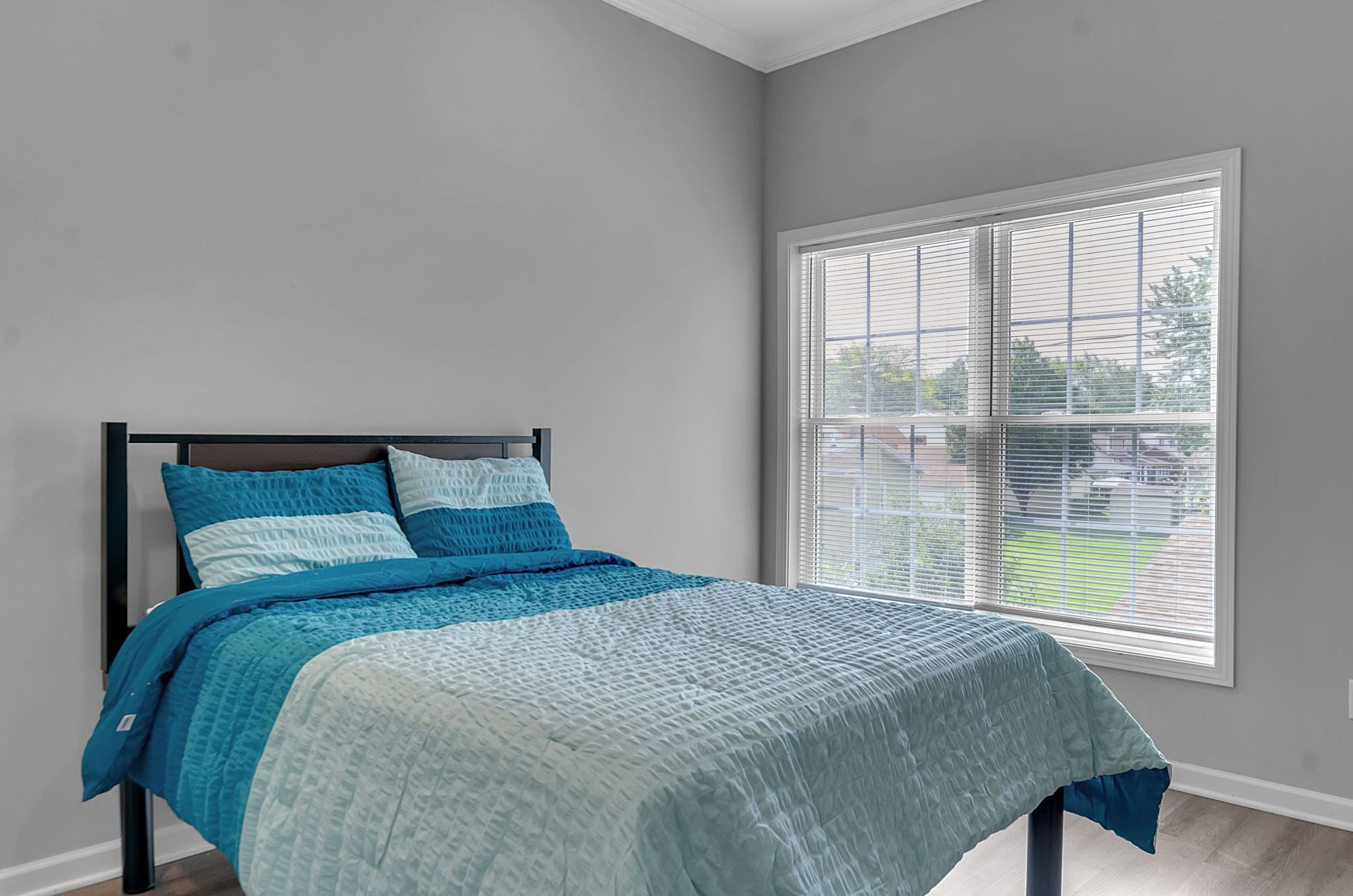 A bedroom with a bed and a window with a blue comforter.