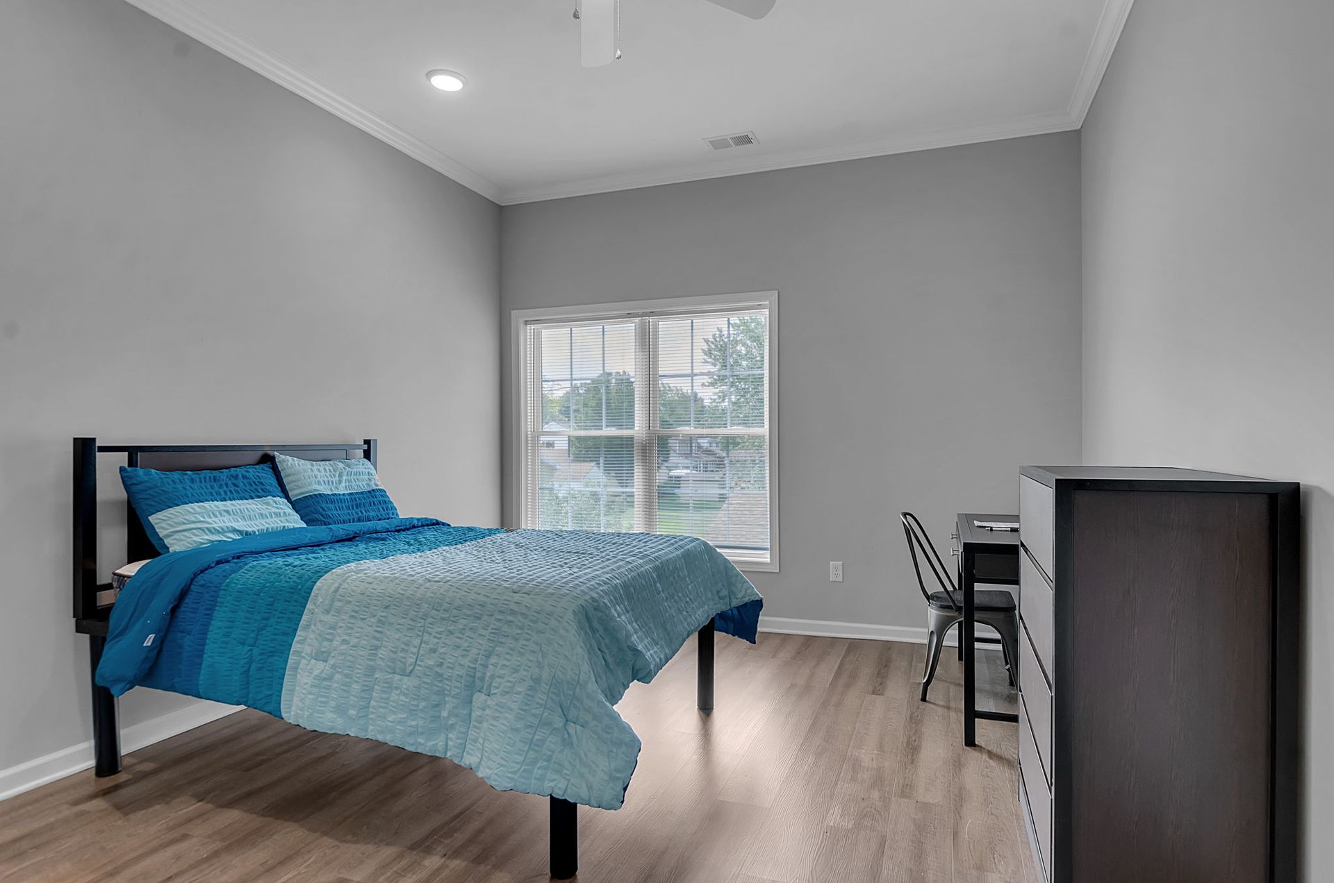 A bedroom with a bed , dresser , desk and chair.
