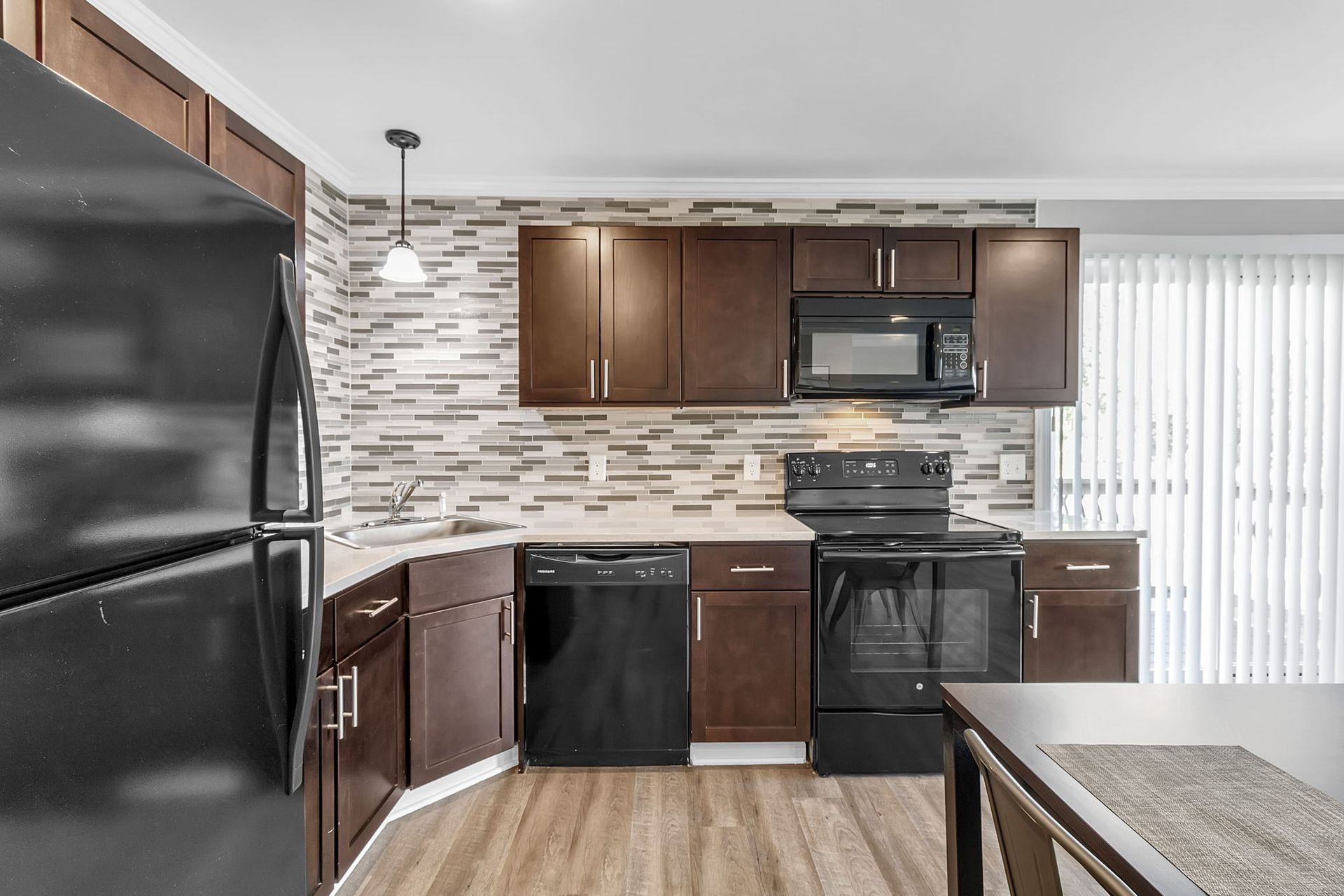 A kitchen with brown cabinets , black appliances and a black refrigerator