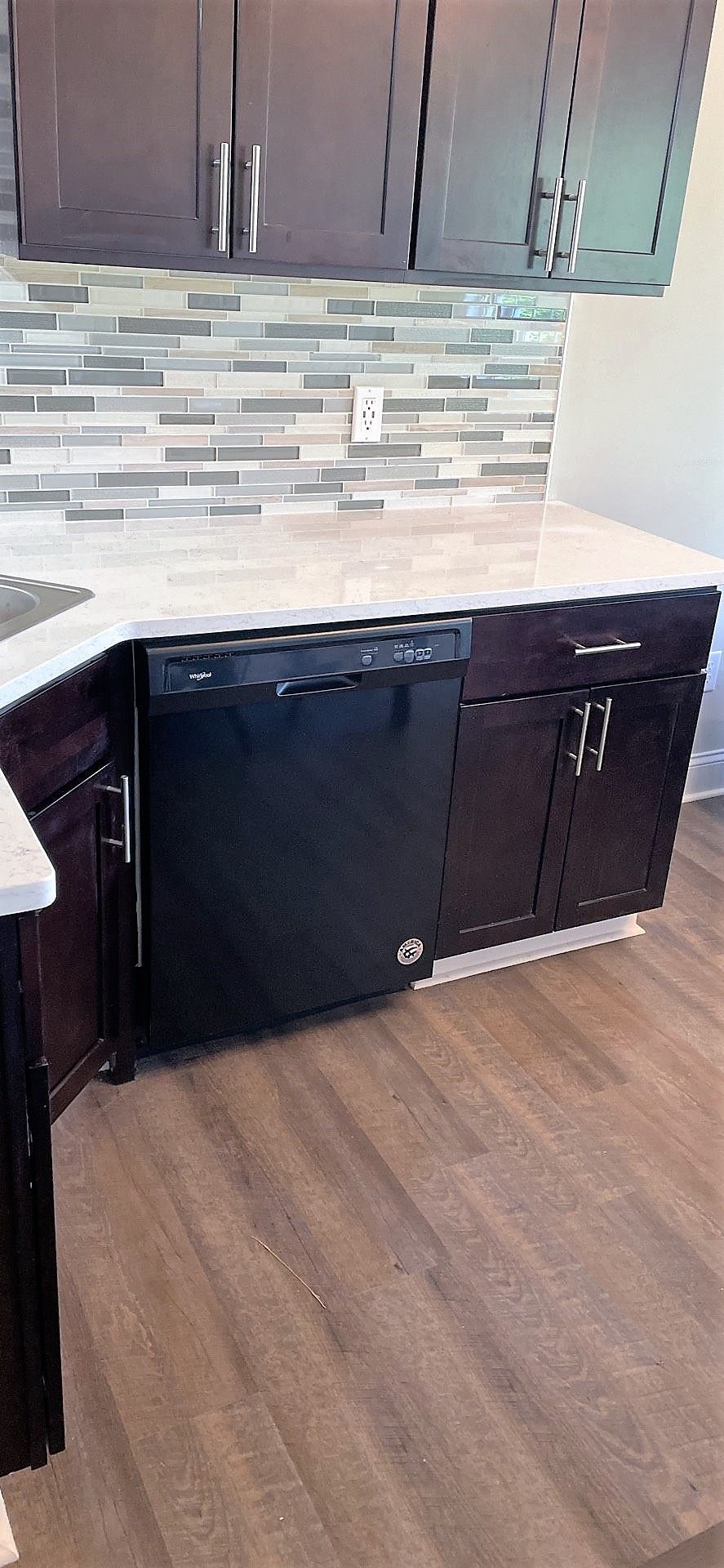 A kitchen with black cabinets and a black dishwasher.