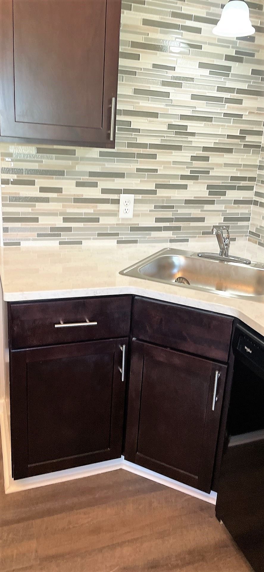 A kitchen with a sink , cabinets , and a dishwasher.