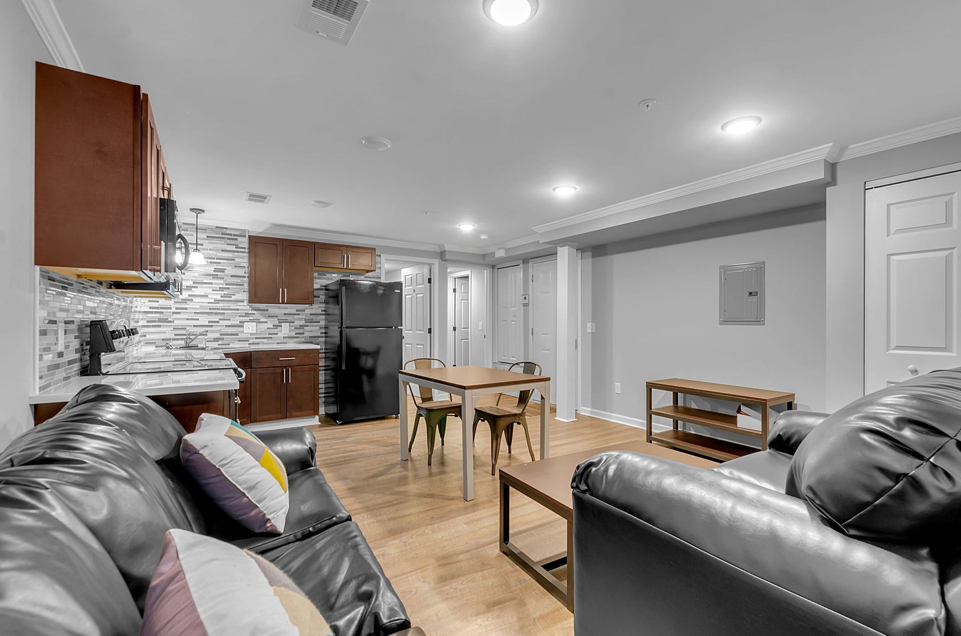 A living room with a couch , table , chairs and a refrigerator.