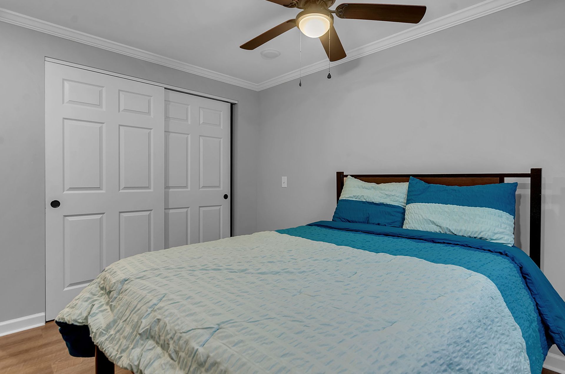 A bedroom with a bed and a ceiling fan.