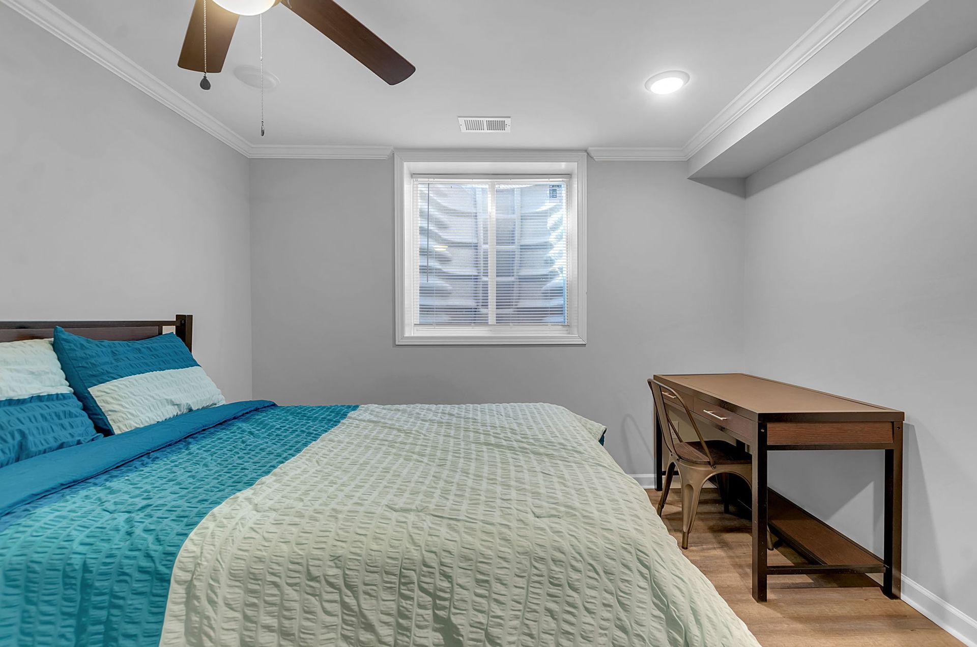 A bedroom with a bed , desk and ceiling fan.