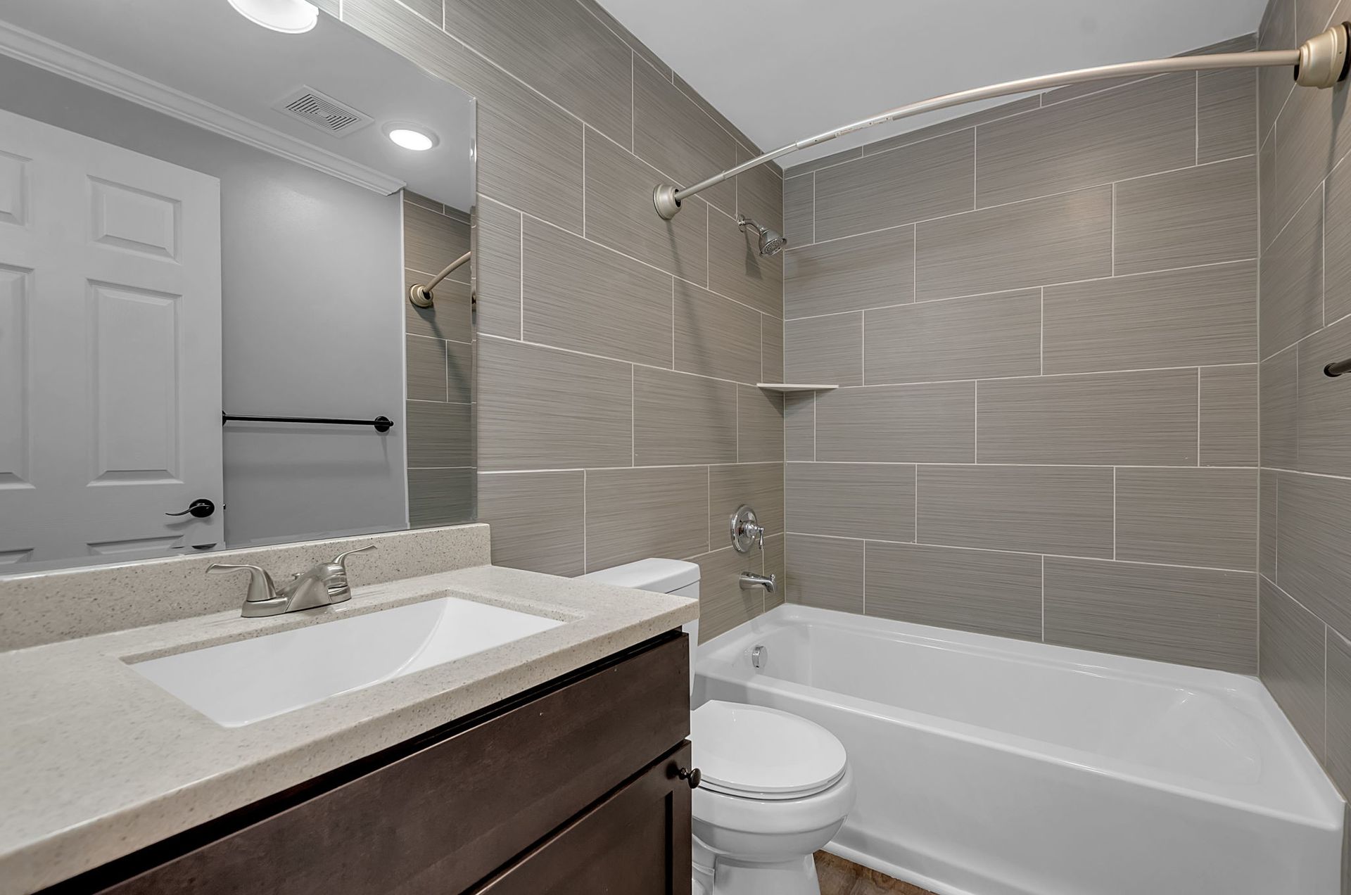 A bathroom with a sink , toilet , tub and mirror.