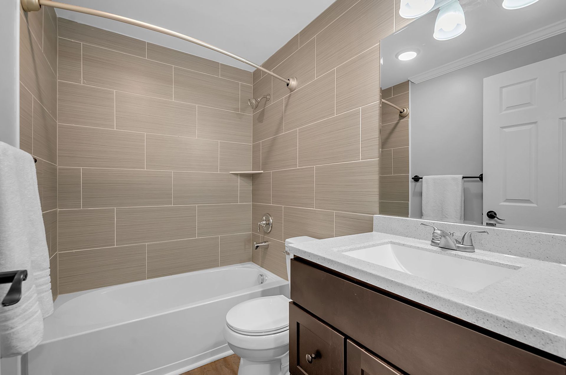 A bathroom with a toilet , sink , bathtub and mirror.