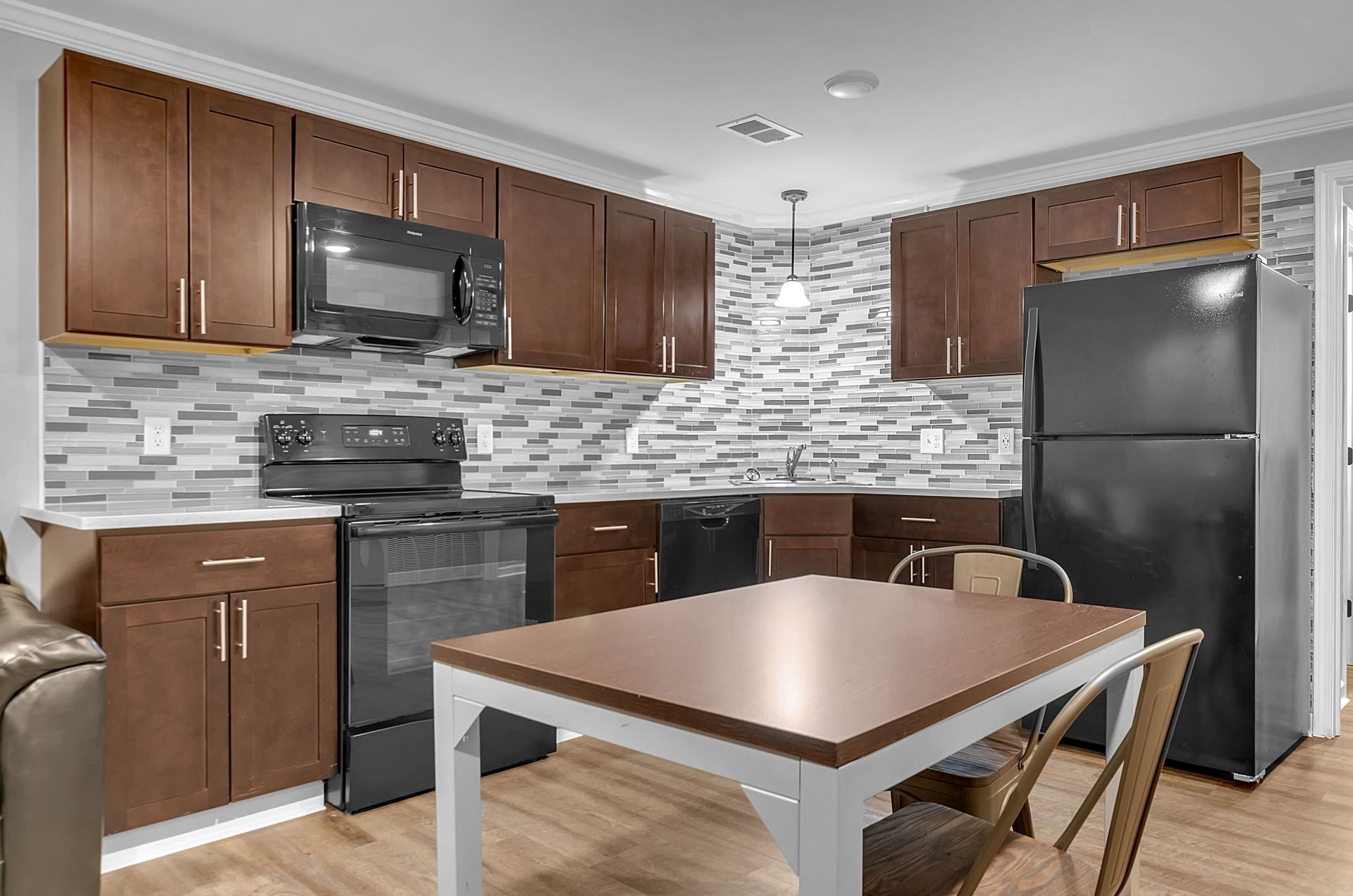 A kitchen with a table , stove , refrigerator and microwave.