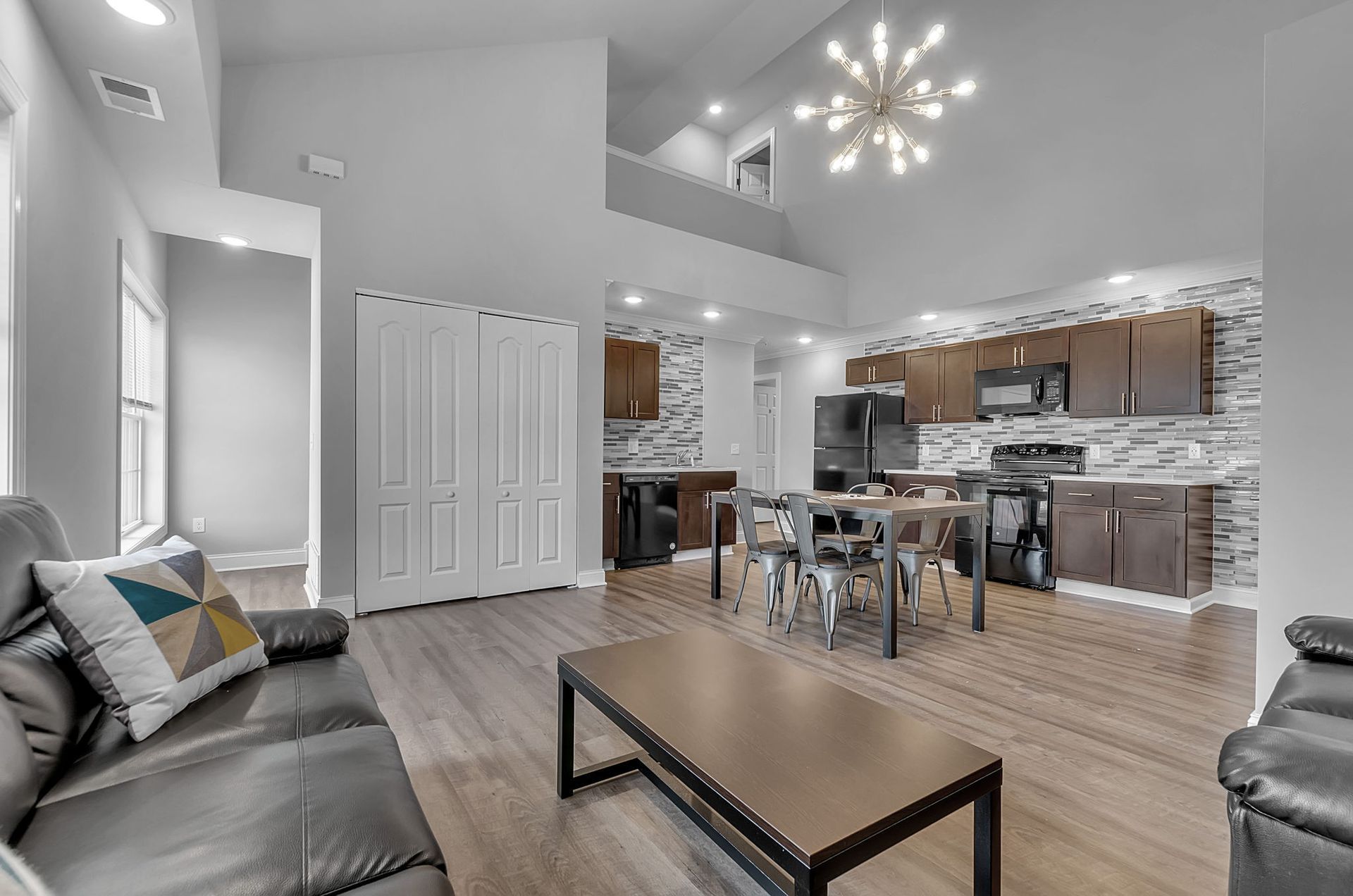 A living room with a couch , table , chairs and a kitchen.
