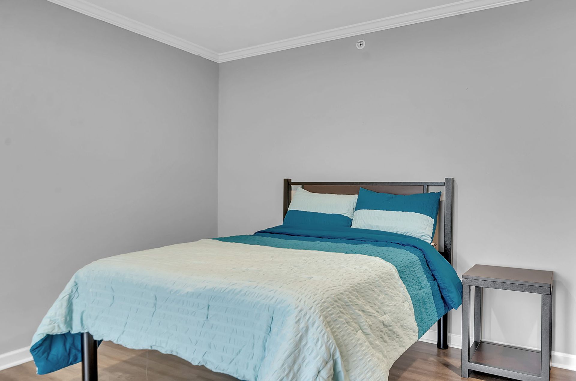 A bedroom with a bed , nightstand , and gray walls.