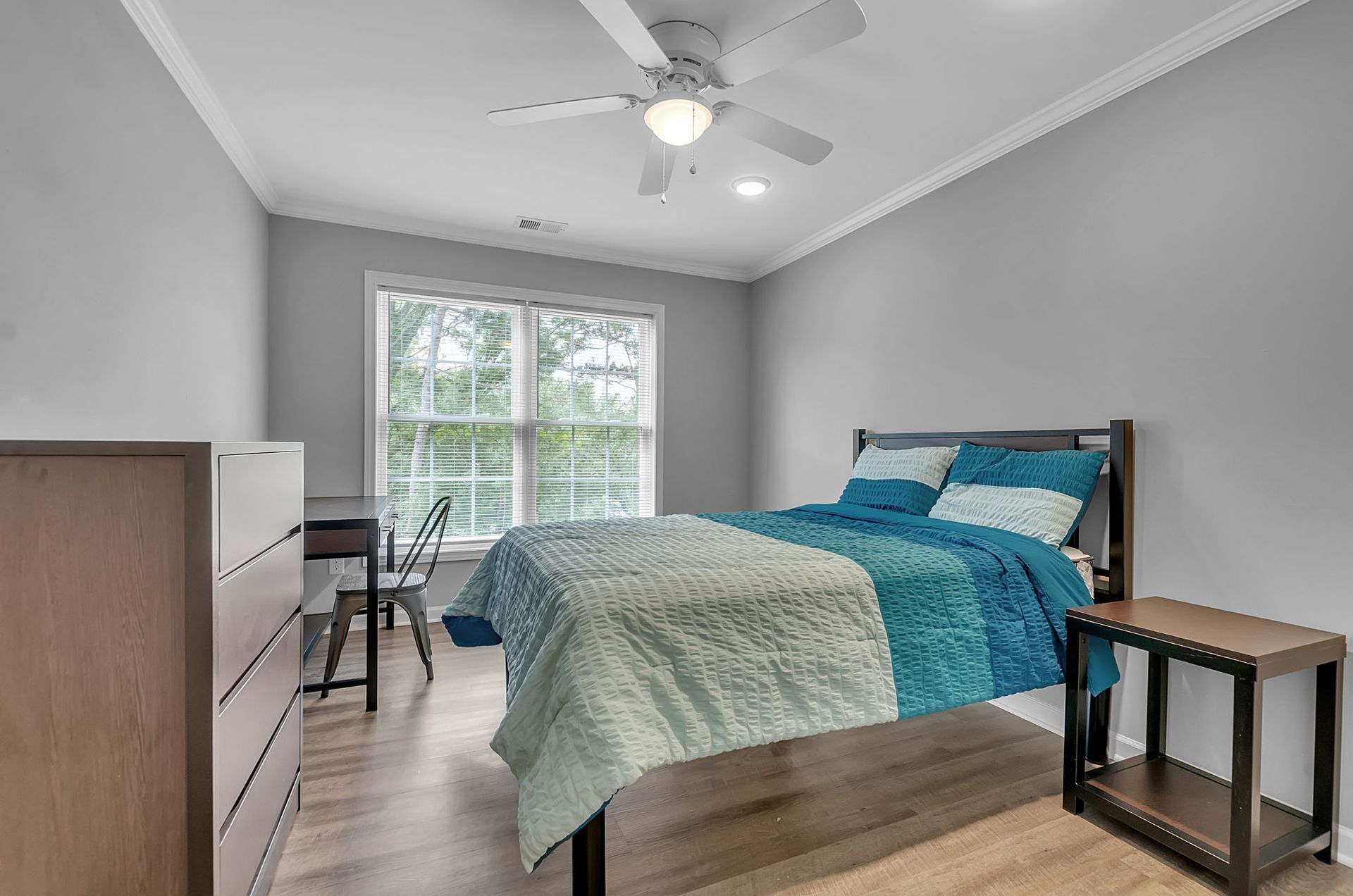 A bedroom with a bed , dresser , nightstand and ceiling fan.