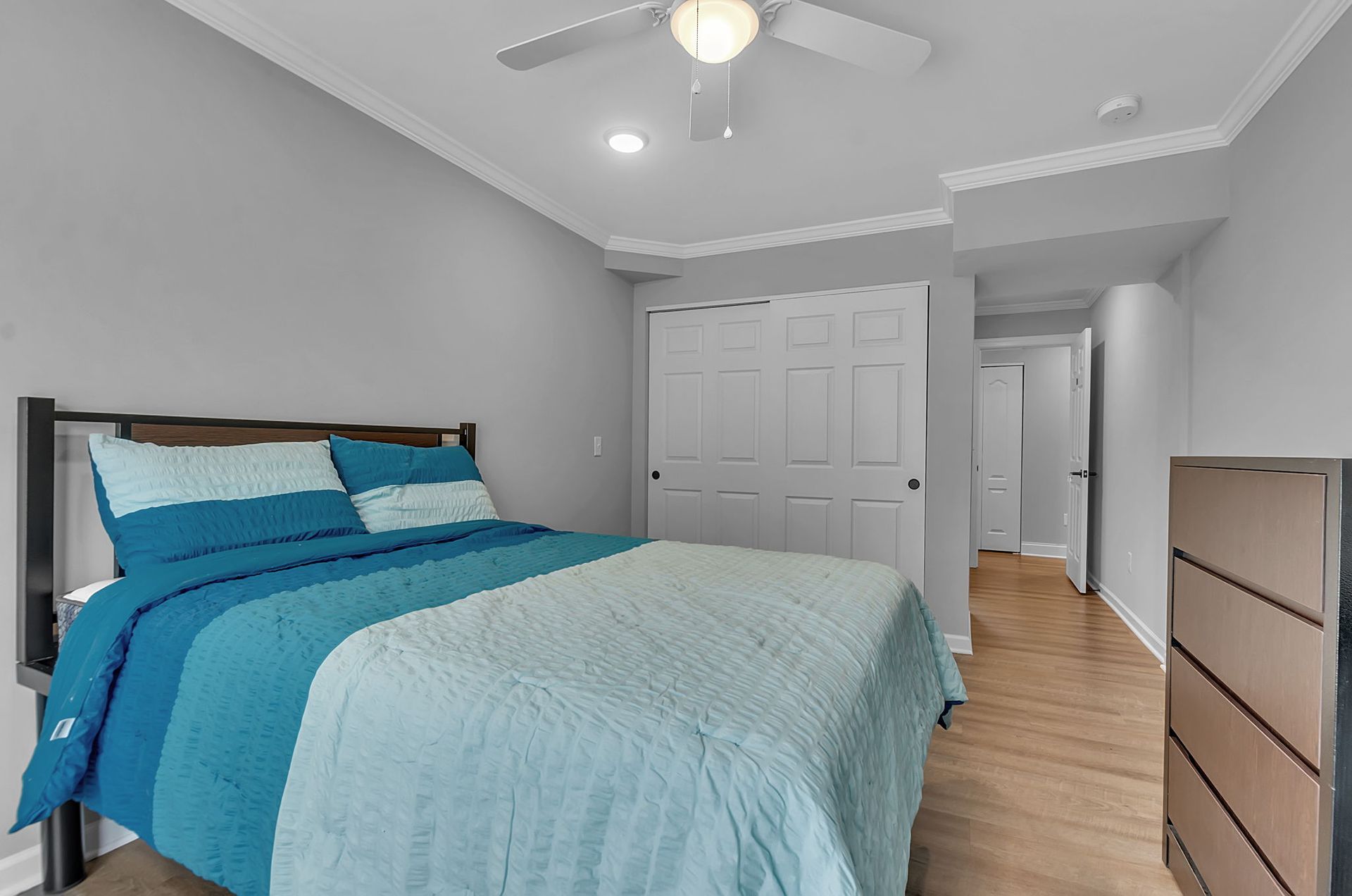 A bedroom with a bed , dresser , and ceiling fan.