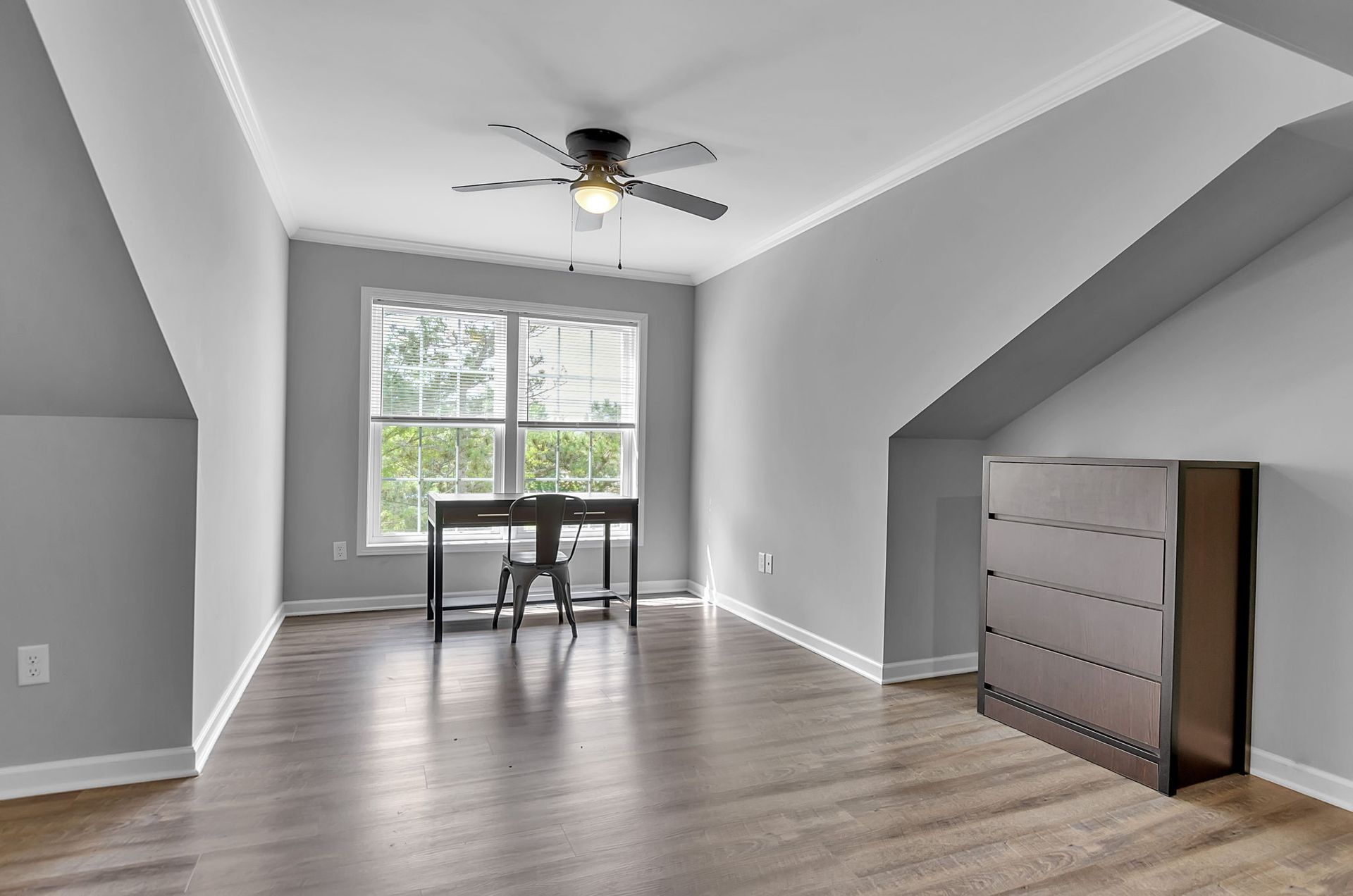 An empty room with a desk and a ceiling fan.