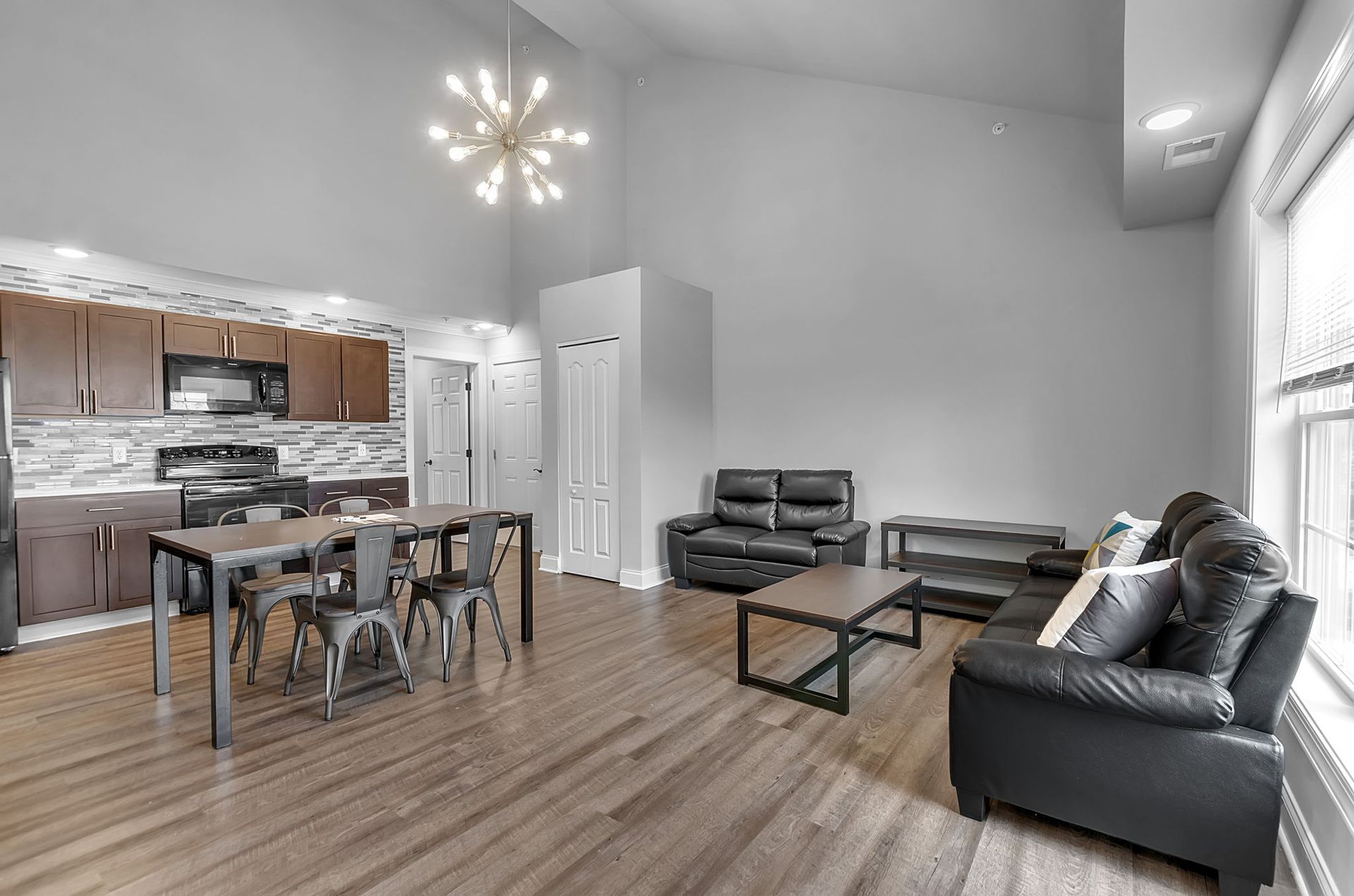 A living room with a couch , table , chairs and a kitchen.