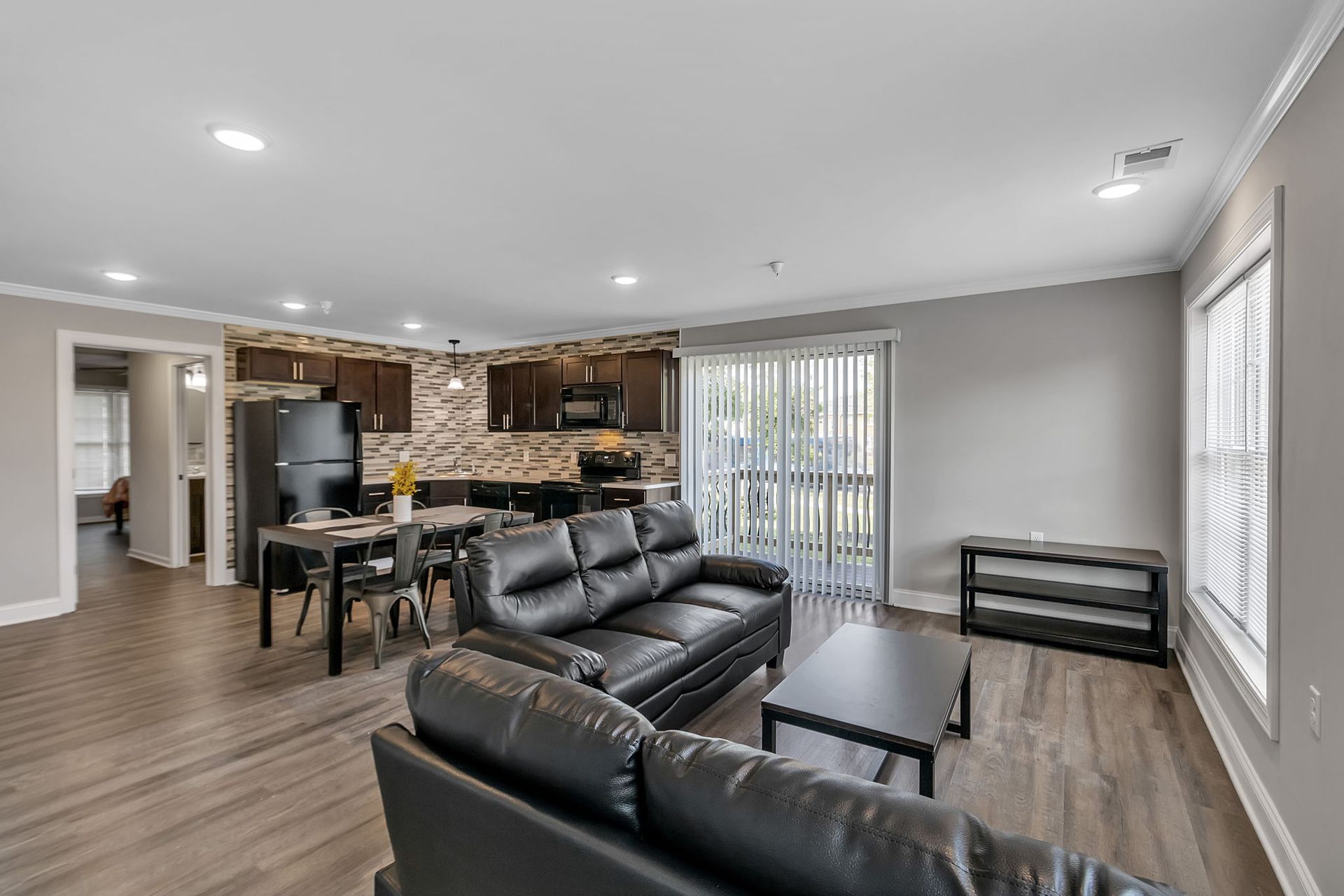 A living room filled with furniture and a sliding glass door leading to a kitchen.