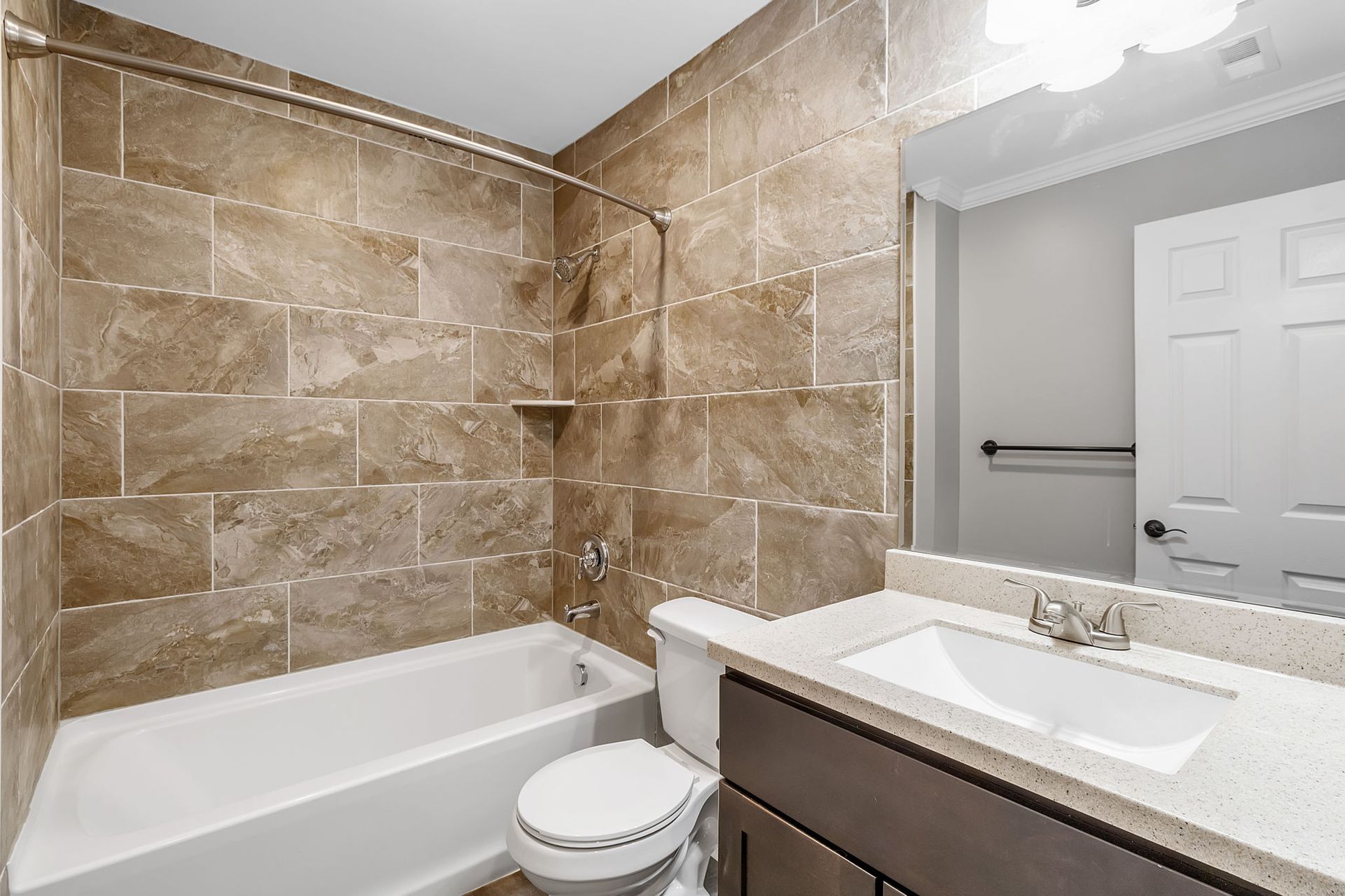 A bathroom with a toilet , sink , bathtub and mirror.