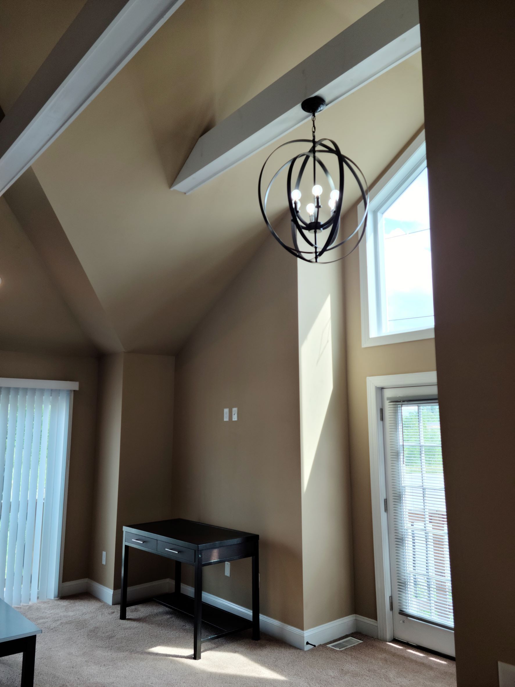 A living room with a table and a chandelier hanging from the ceiling