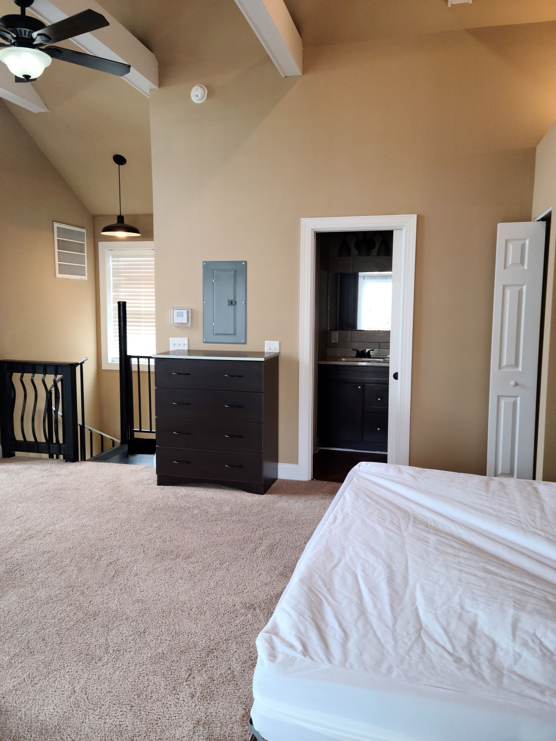 A bedroom with a bed and a ceiling fan