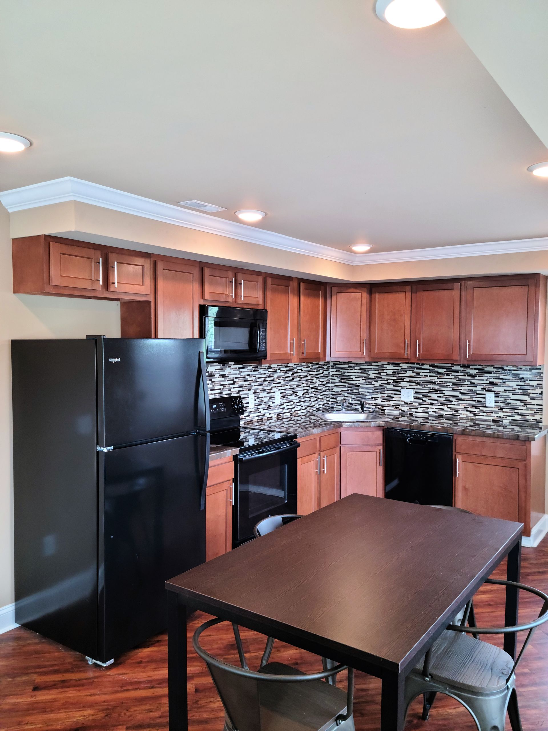 A kitchen with a table and chairs and a black refrigerator