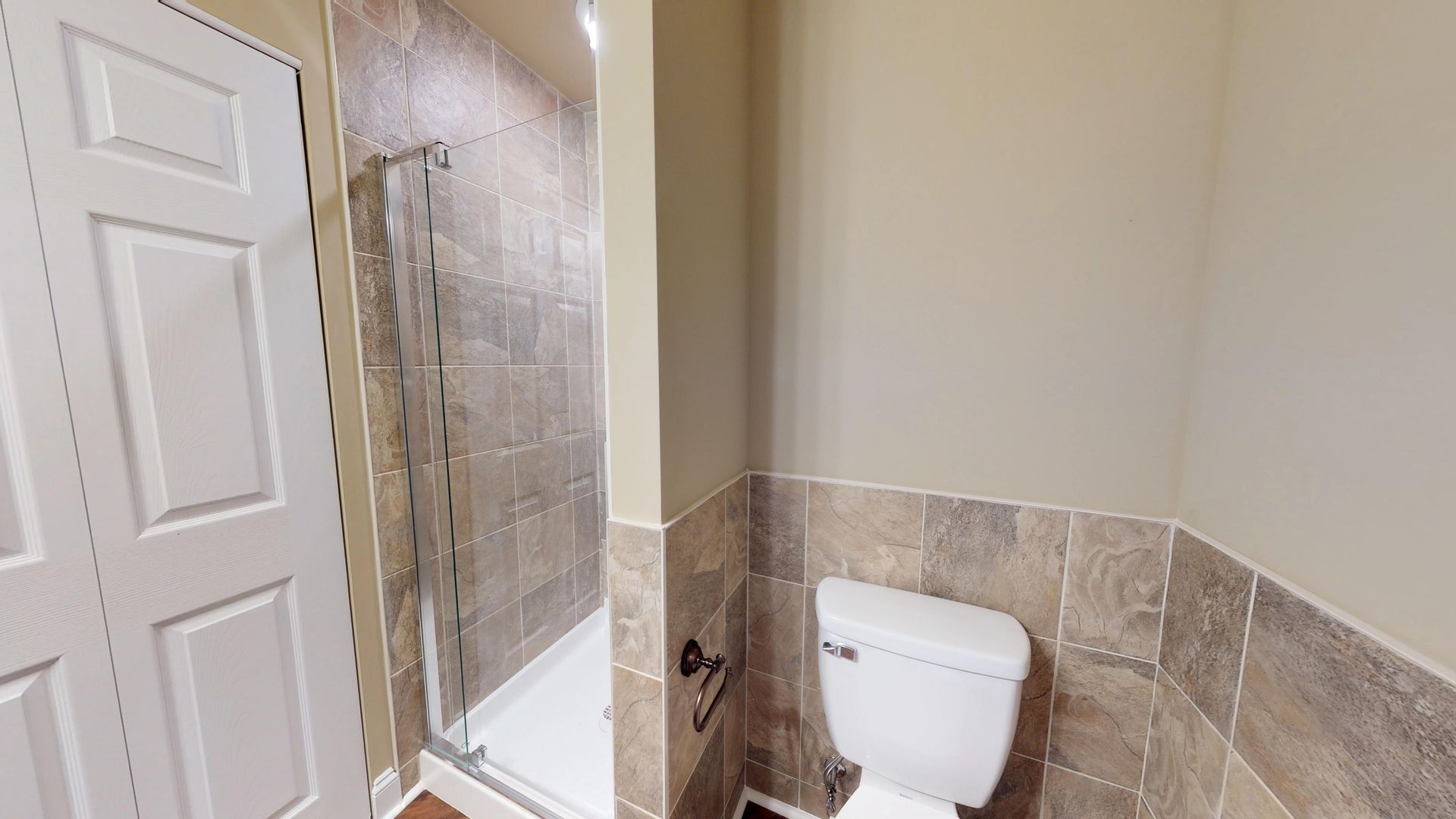 A bathroom with a toilet and a walk in shower.