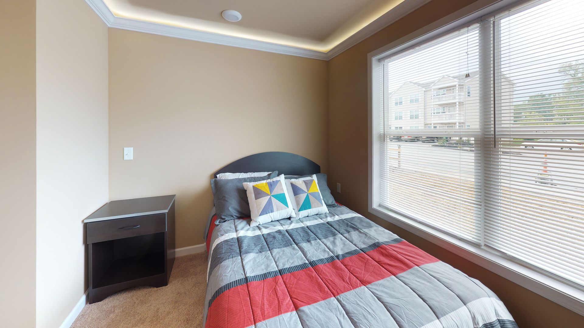 A bedroom with a single bed , nightstand , and window.