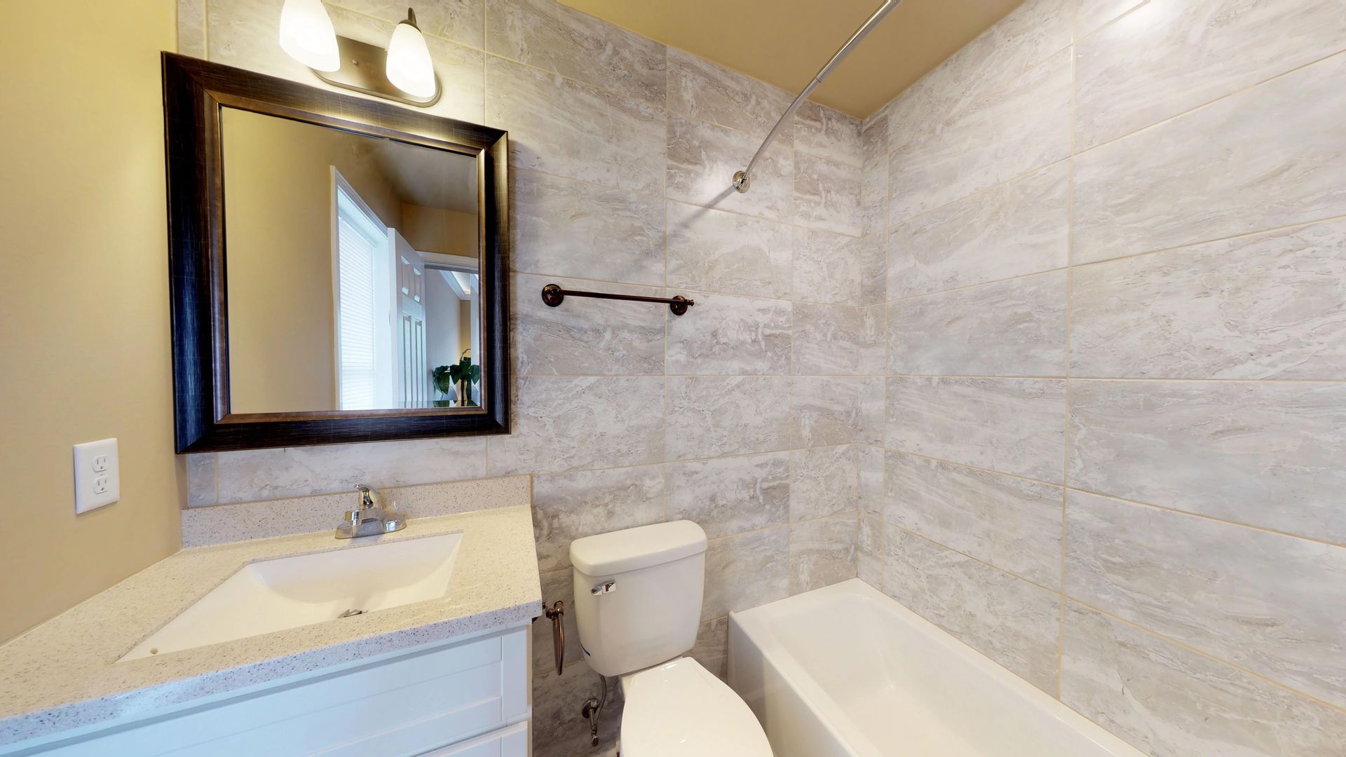 A bathroom with a toilet , sink , mirror and bathtub.