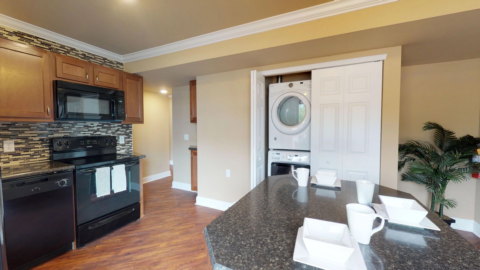 A kitchen with a washer and dryer stacked on top of each other.