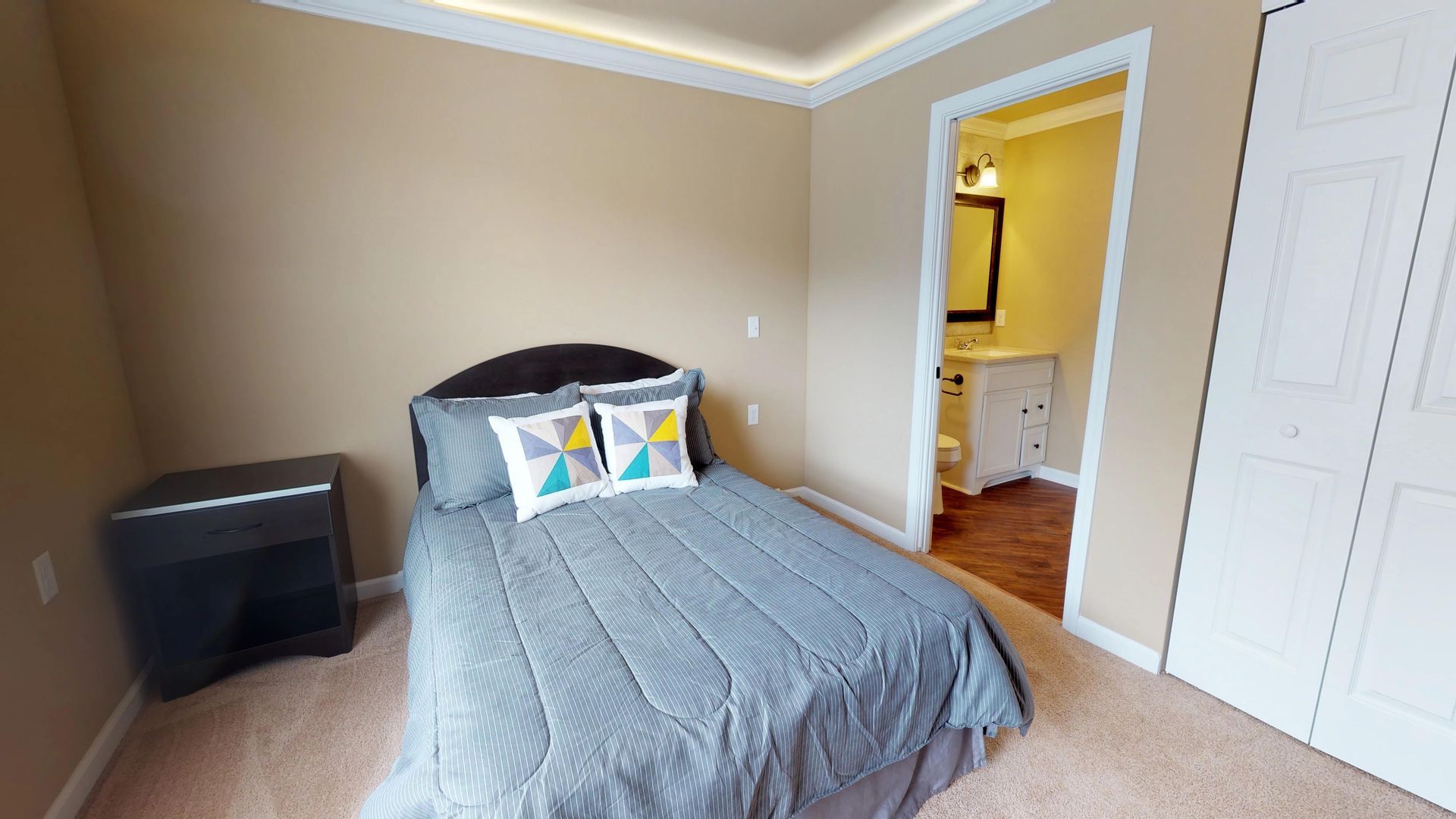 A bedroom with a bed , nightstand , and bathroom.